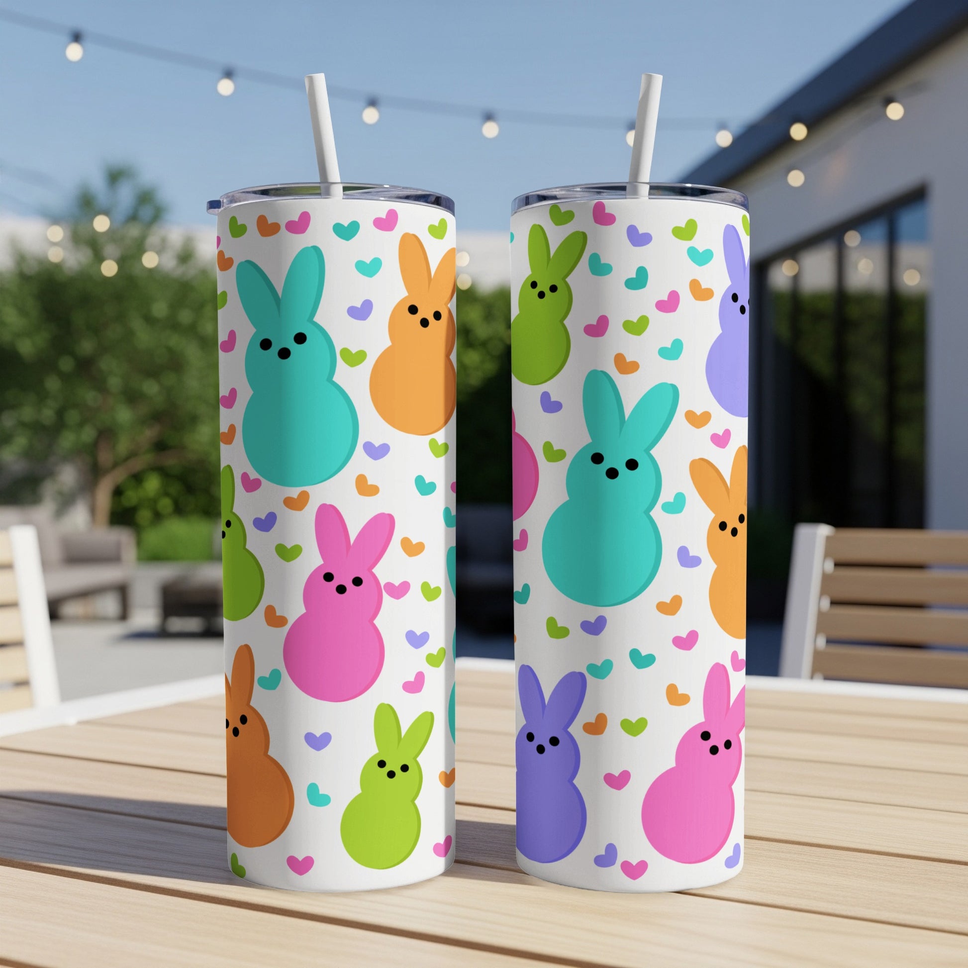 Two colorful bunny-shaped tumblers with heart pattern sit on a wooden table.