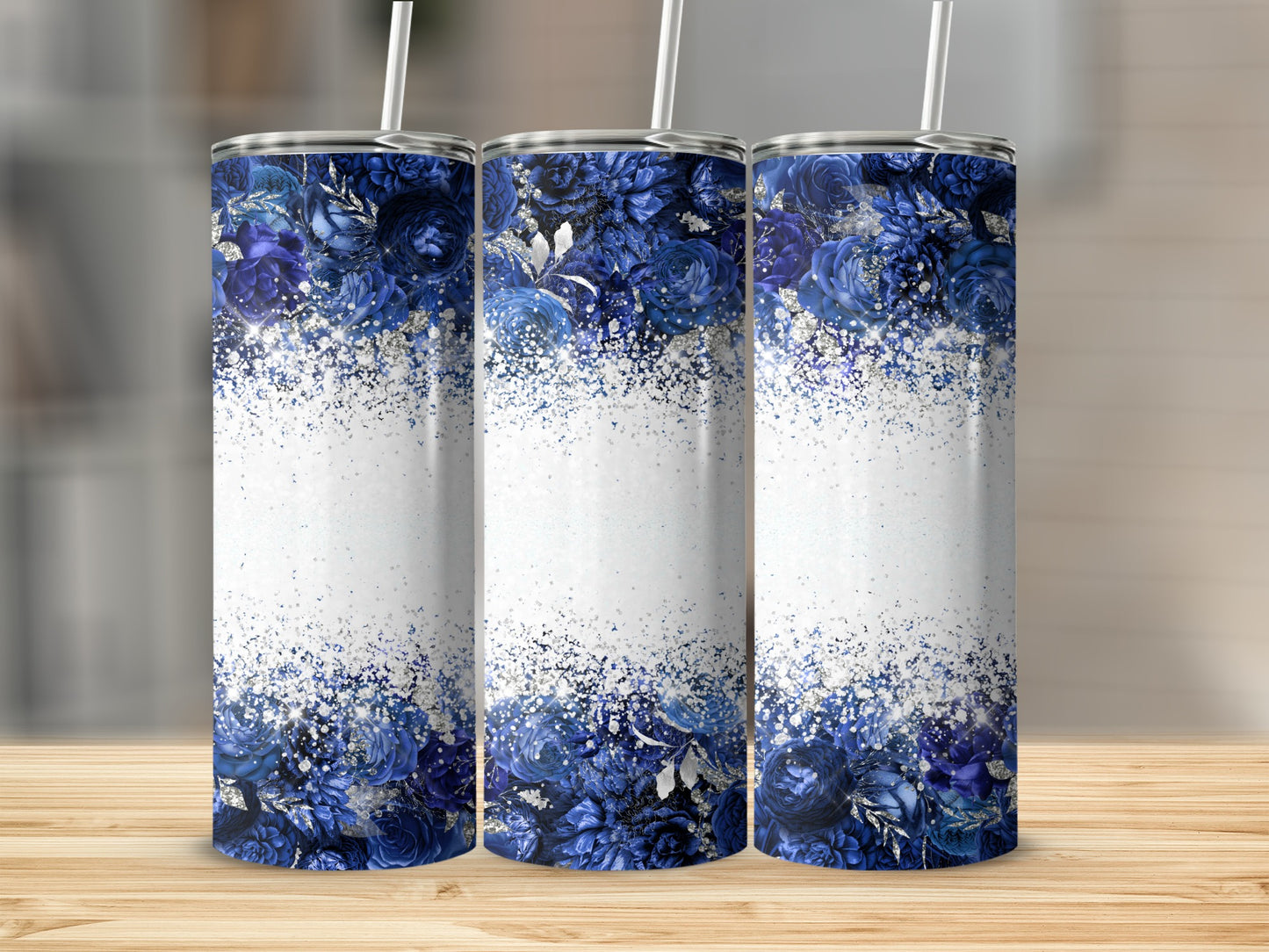 Three blue floral tumblers with glitter accents on a wooden surface.