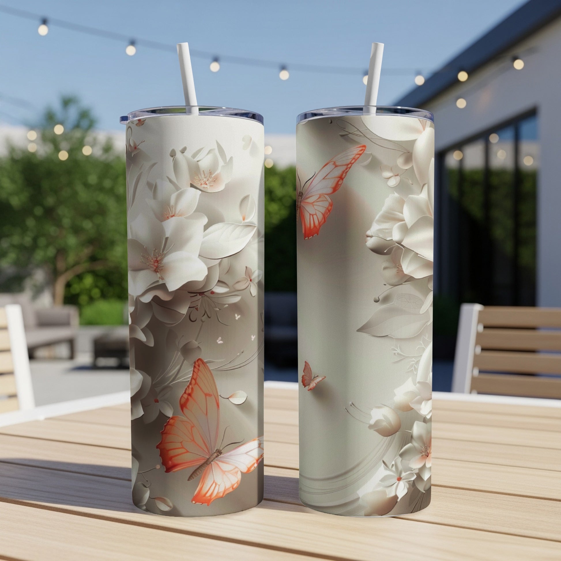 Two tall tumblers with butterfly and floral designs on a wooden table.