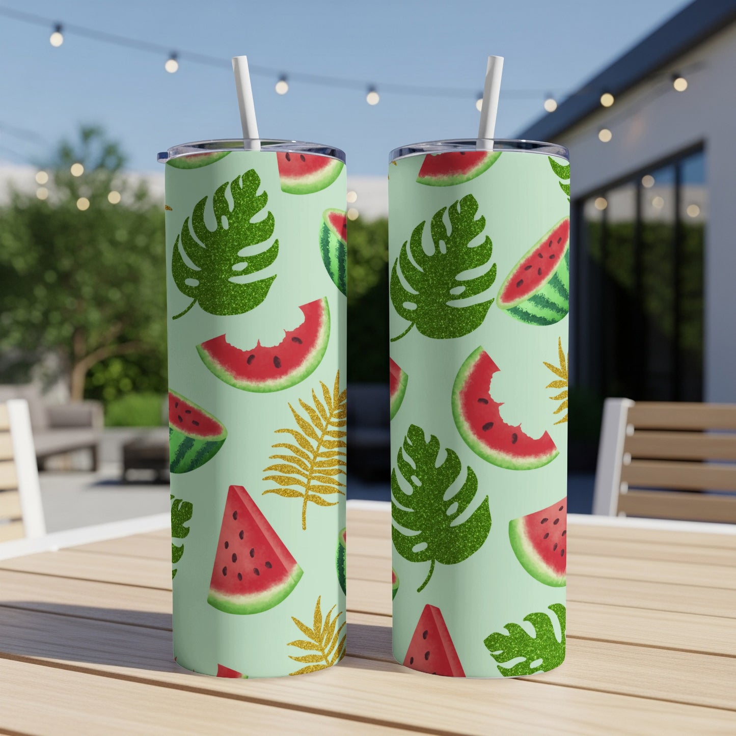Two tall tumblers with watermelon and tropical leaf pattern on a wooden table.