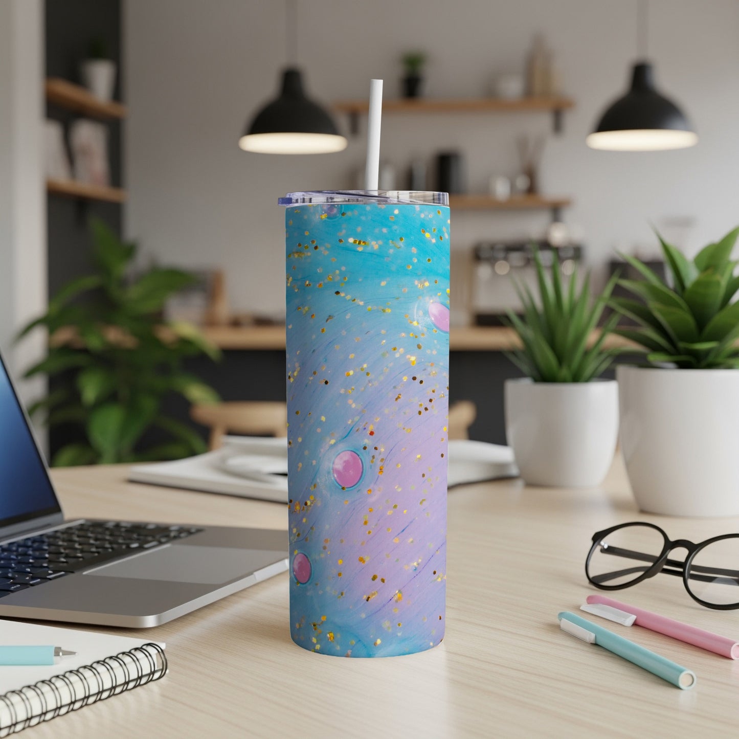 Blue and pink glitter tumbler with straw on a desk.