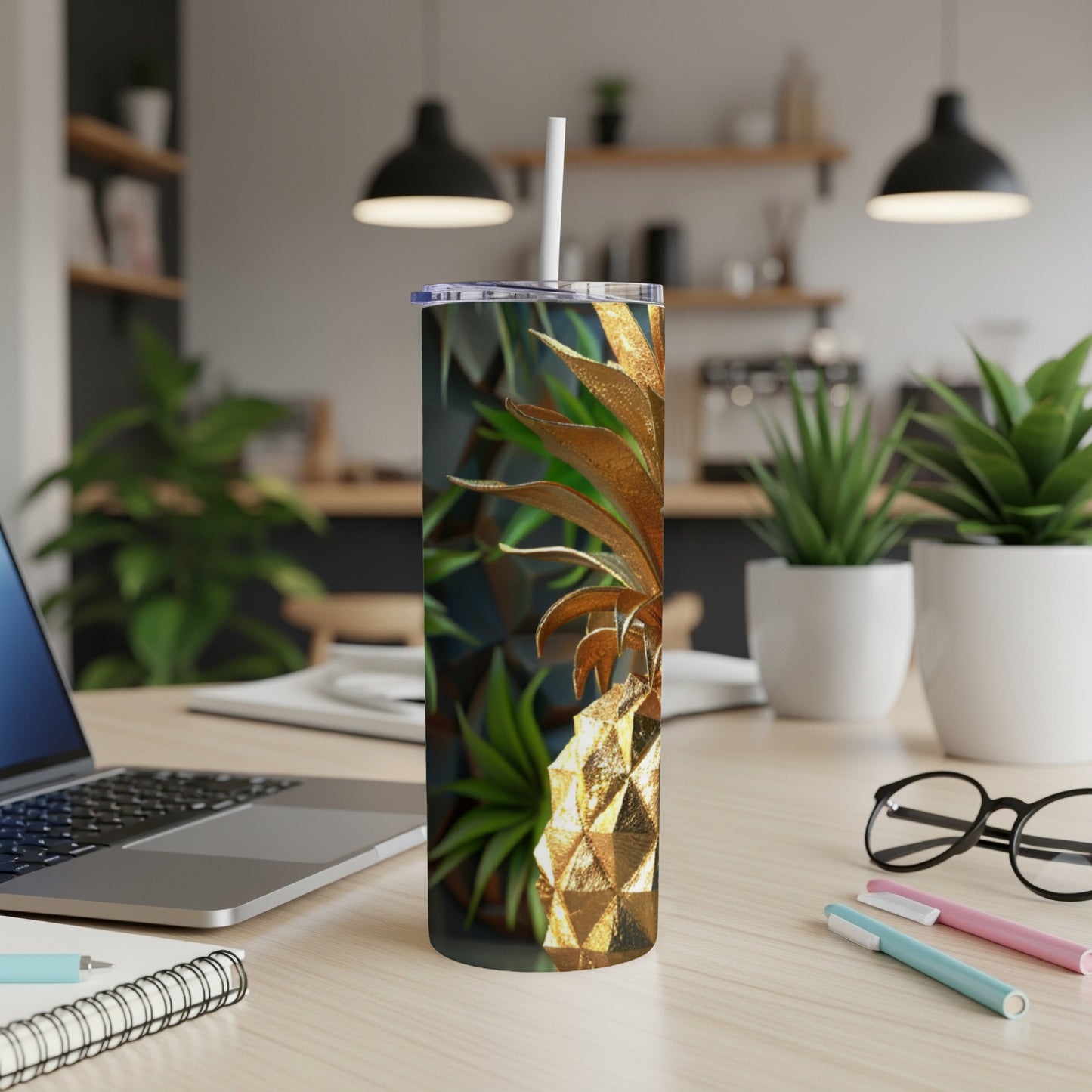 Gold pineapple tumbler with straw on a desk.