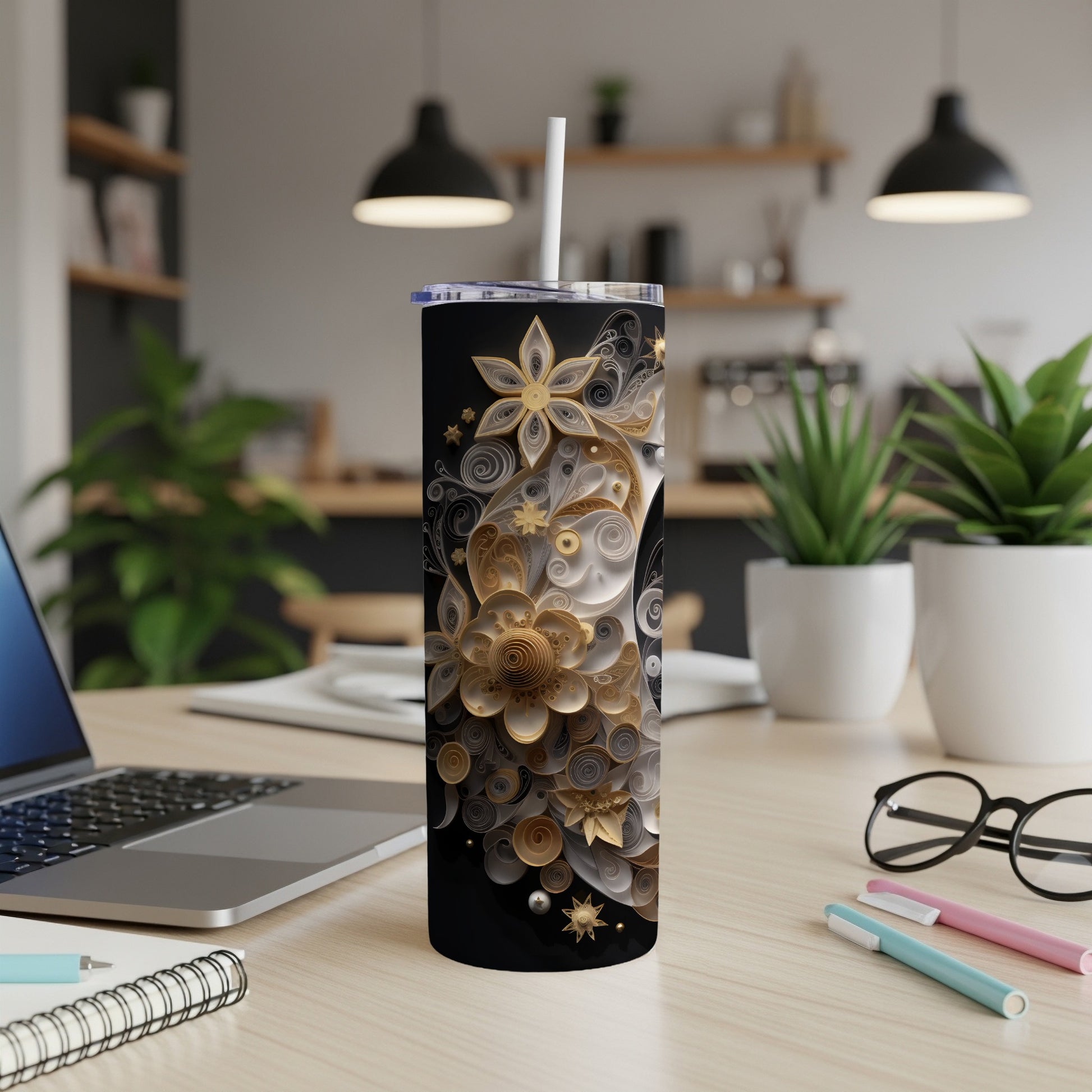 Black tumbler with ornate gold and silver floral pattern and white straw.