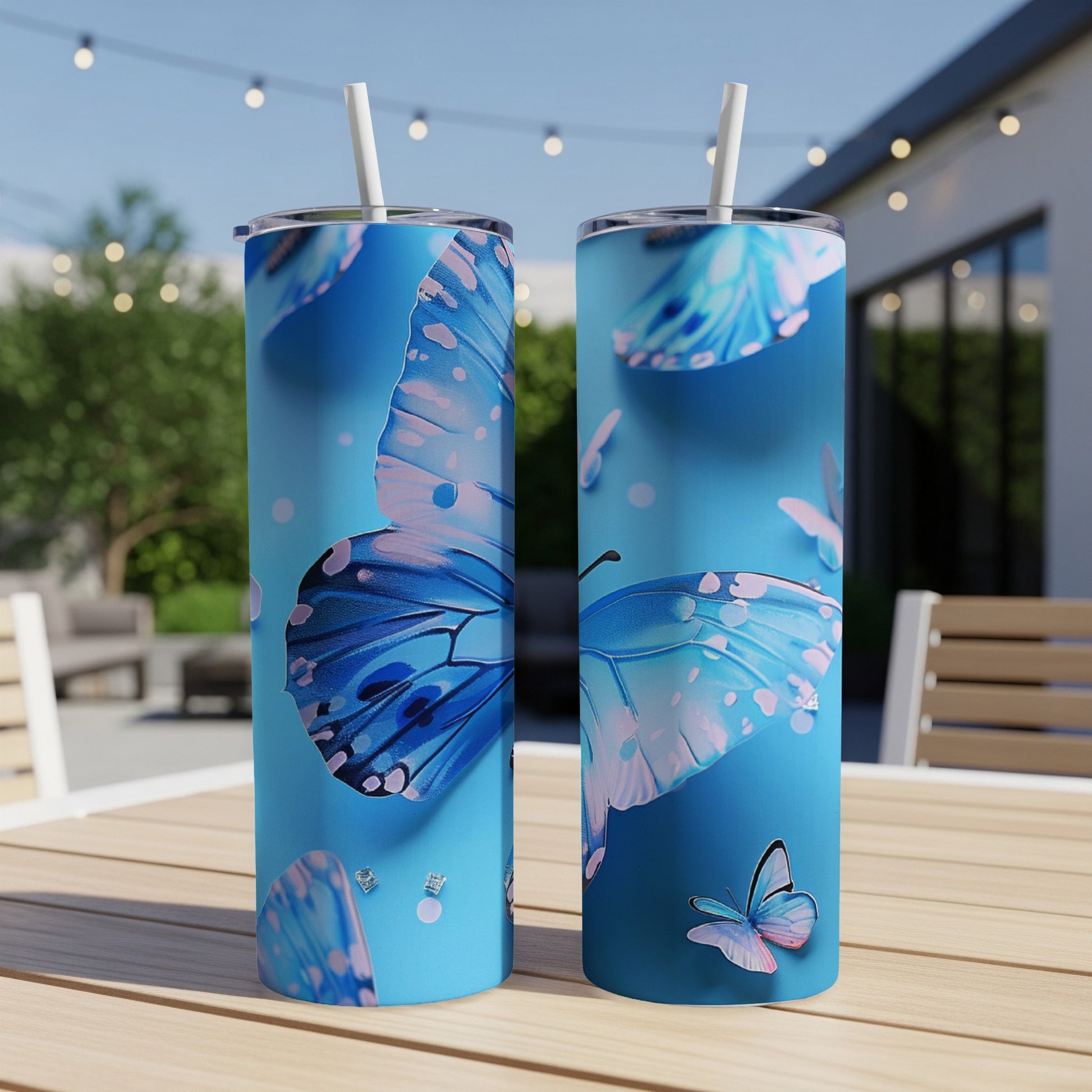 Two blue butterfly tumblers with straws on a wooden table.