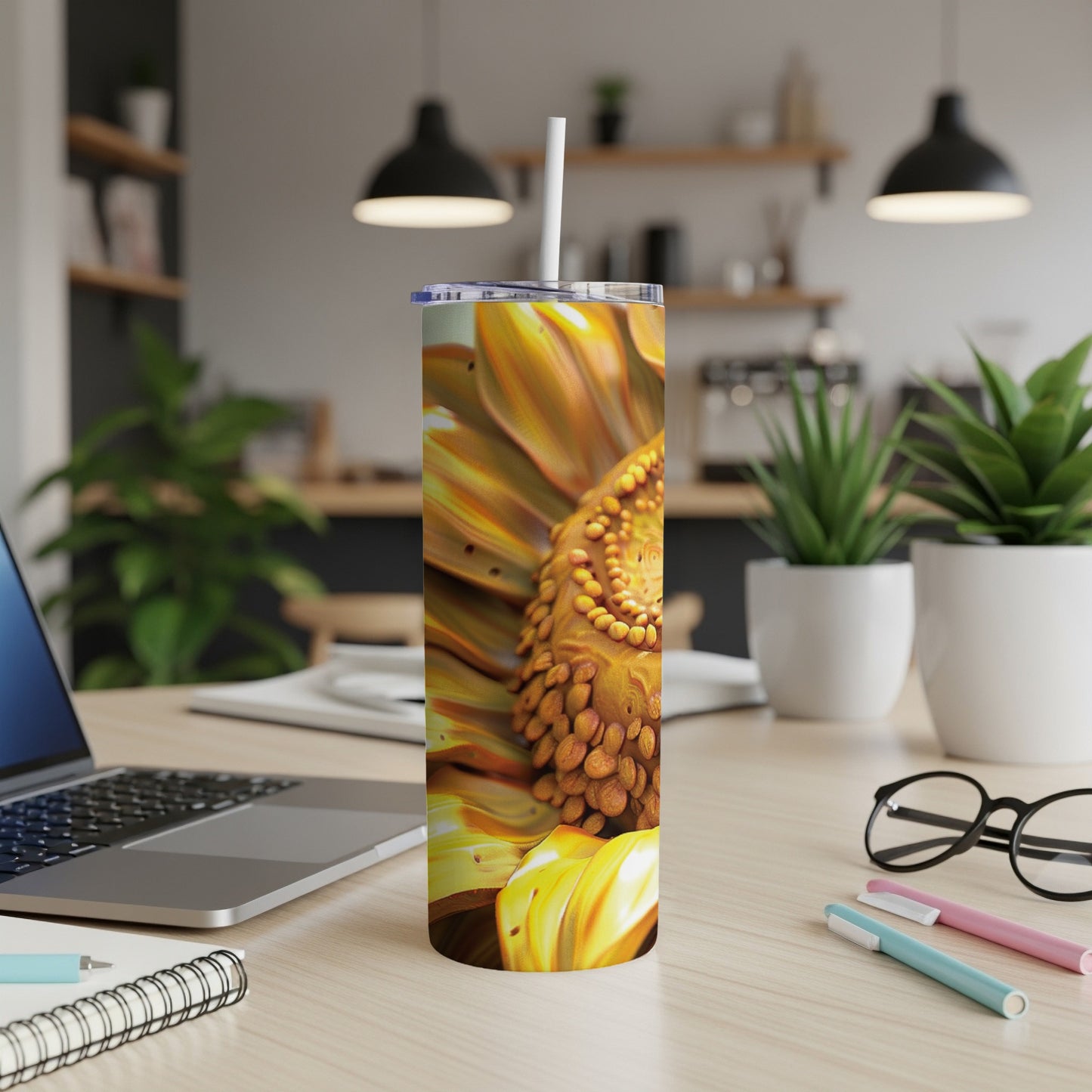Close-up of a sunflower on a travel tumbler with a straw, on a desk.
