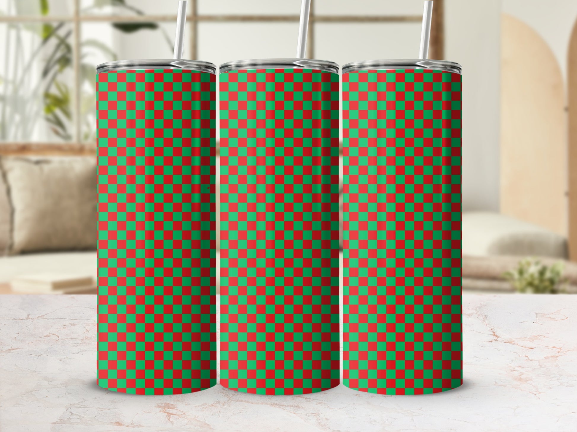 Three green and red checkered tumblers with straws on a marble surface.