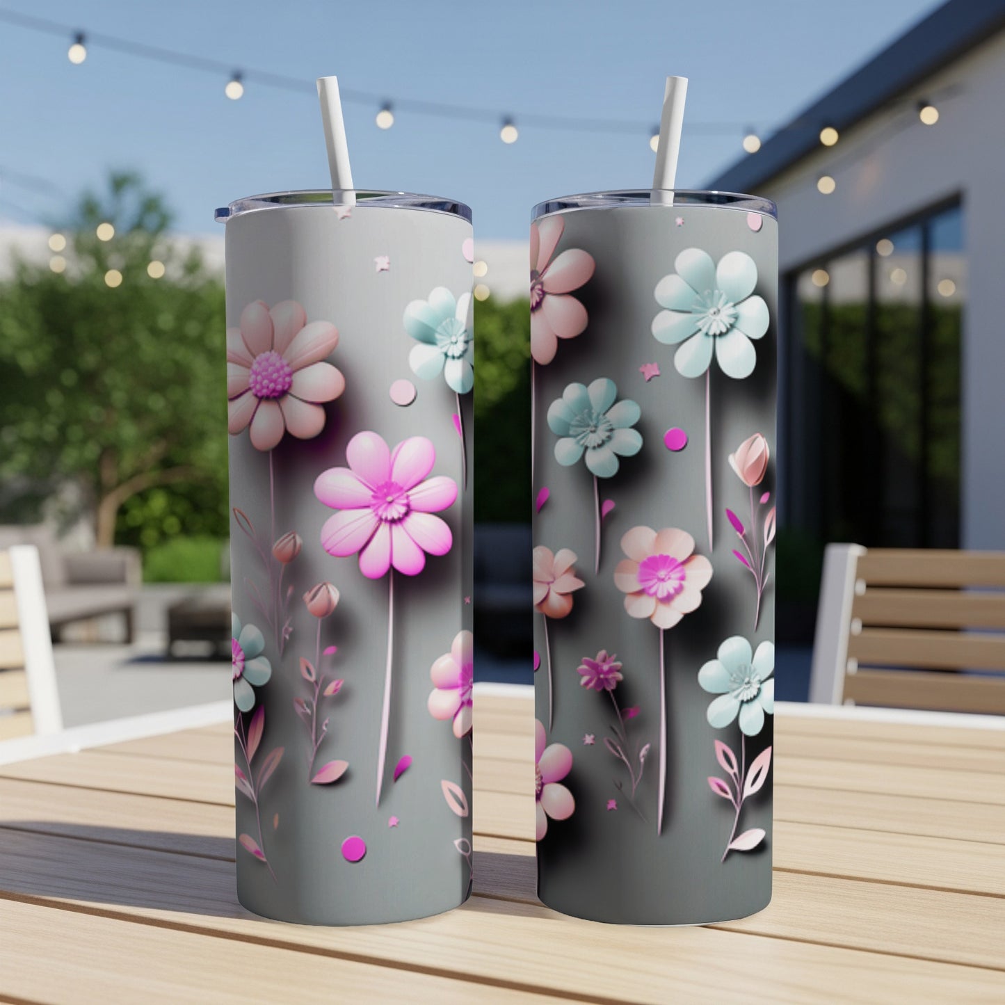 Two gray tumblers with pastel flowers and straws on a wooden table.