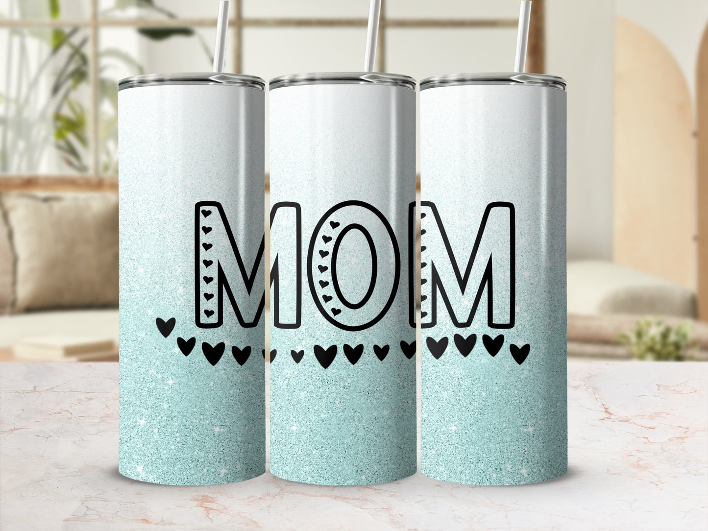 Glittery tumbler with "MOM" and hearts on a light marble surface.