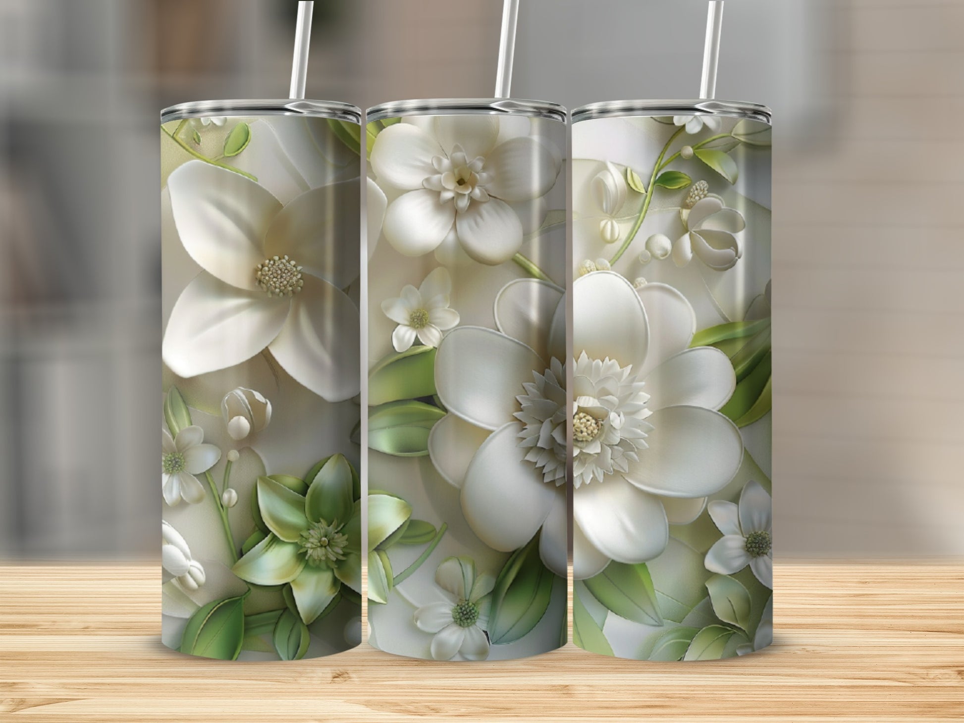 Three tumblers featuring white and green floral designs on a wooden surface.