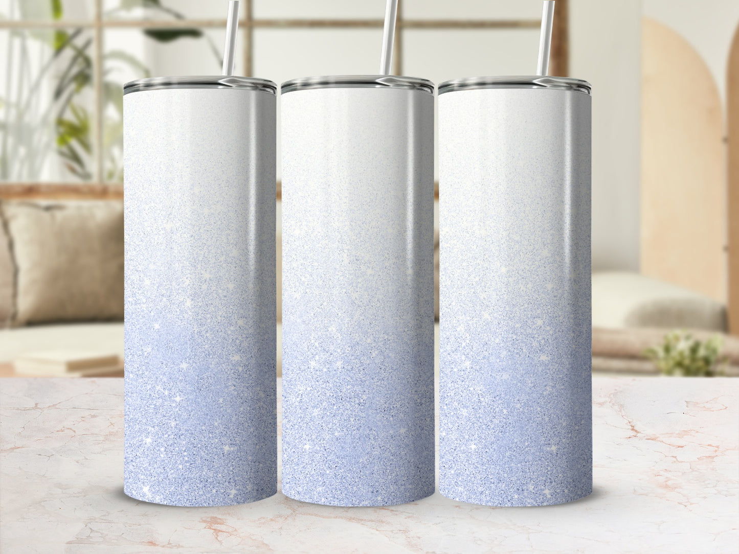 Three white and pale blue glitter tumblers with straws on a marble surface.