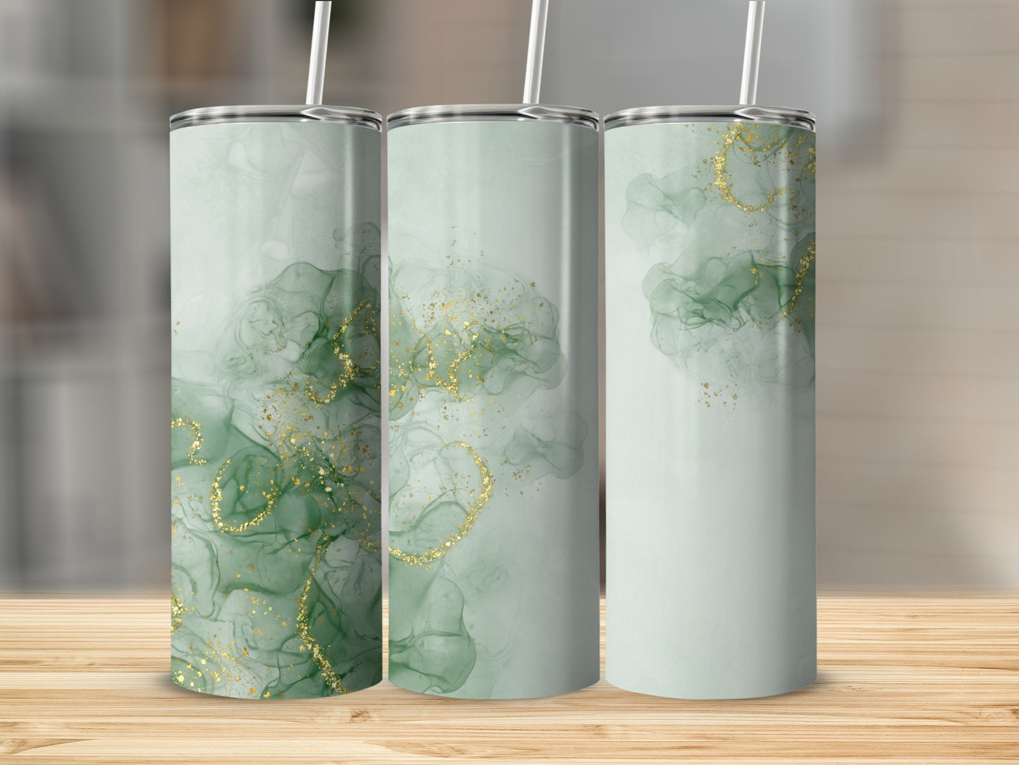 Three green tumblers with gold glitter accents, displayed on a wooden surface.
