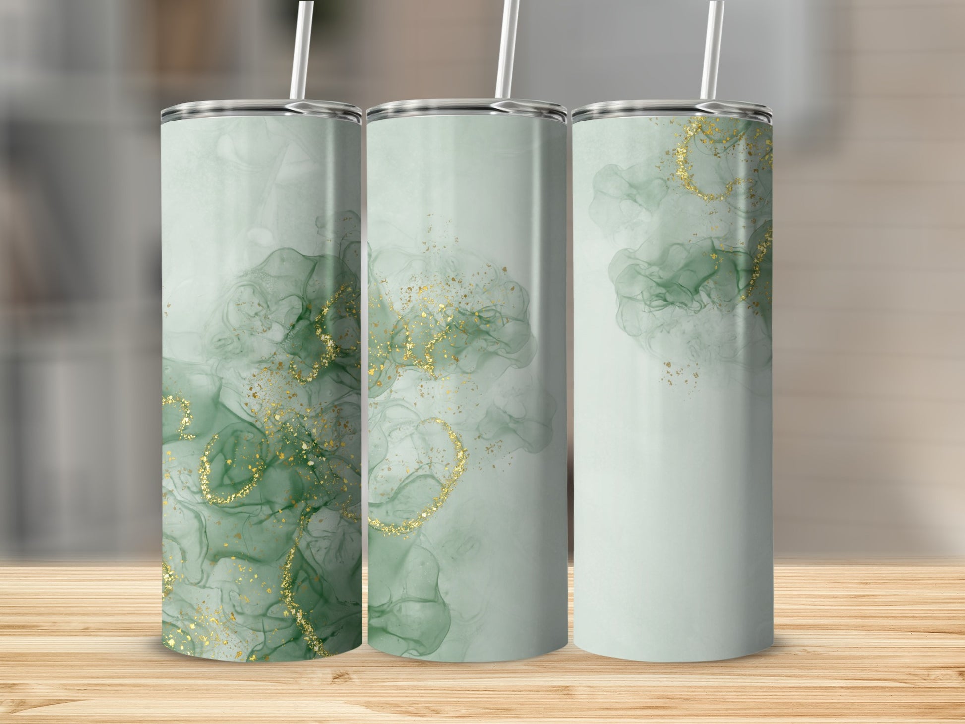 Three green tumblers with gold glitter accents, displayed on a wooden surface.