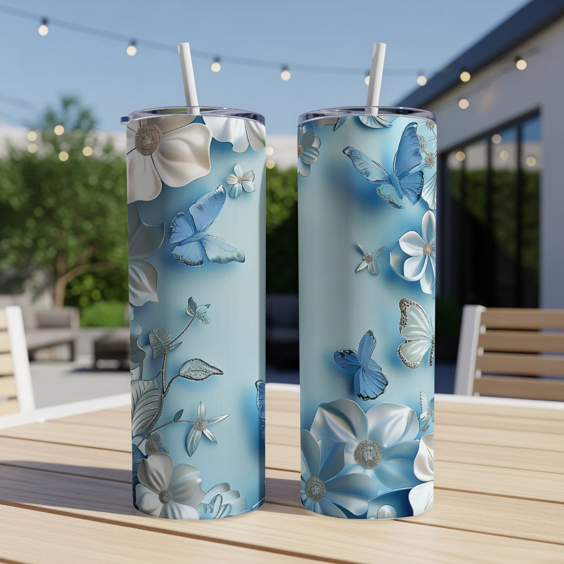 Two light blue tumblers with white and silver floral and butterfly designs.