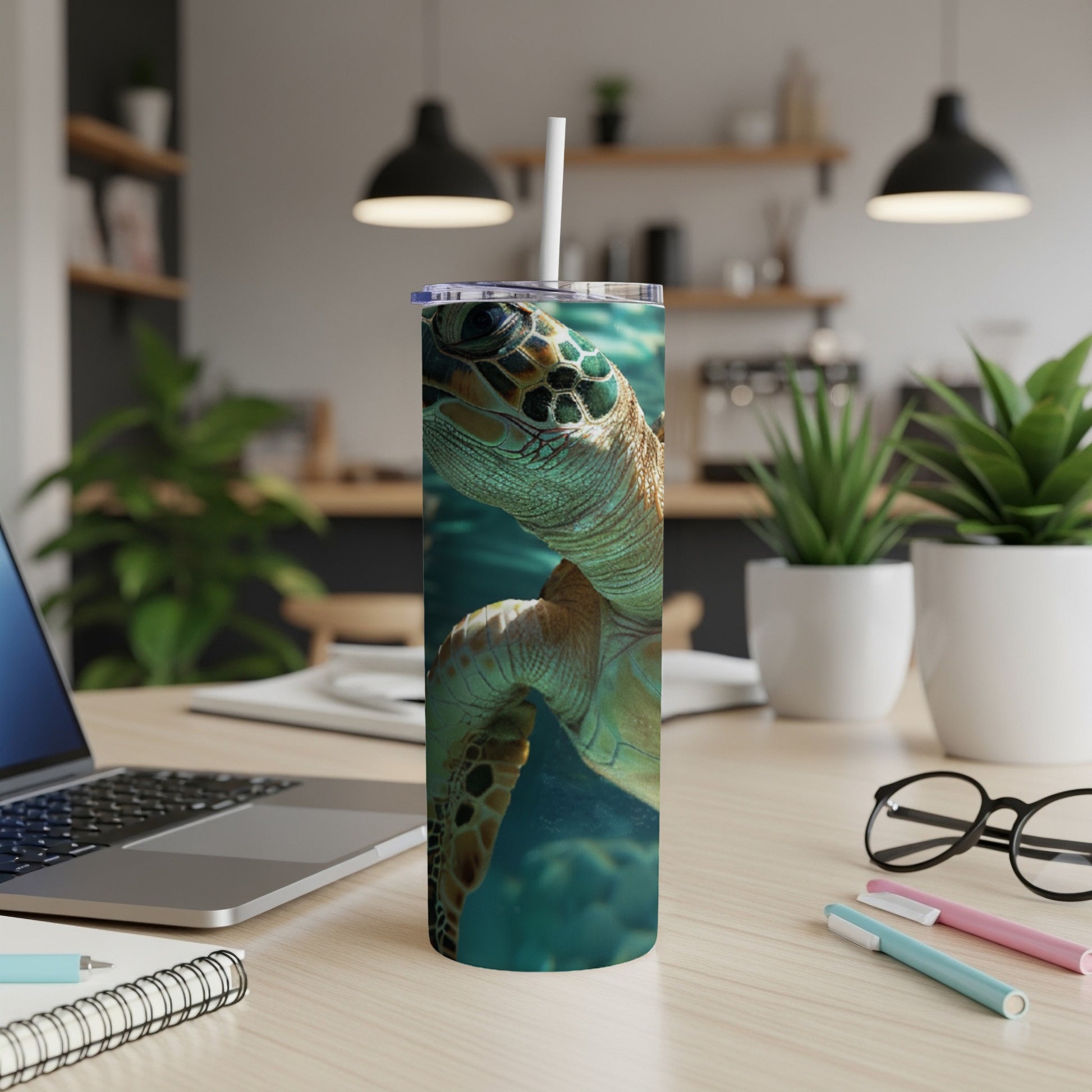 Sea turtle design on a white tumbler with a straw, on a desk.