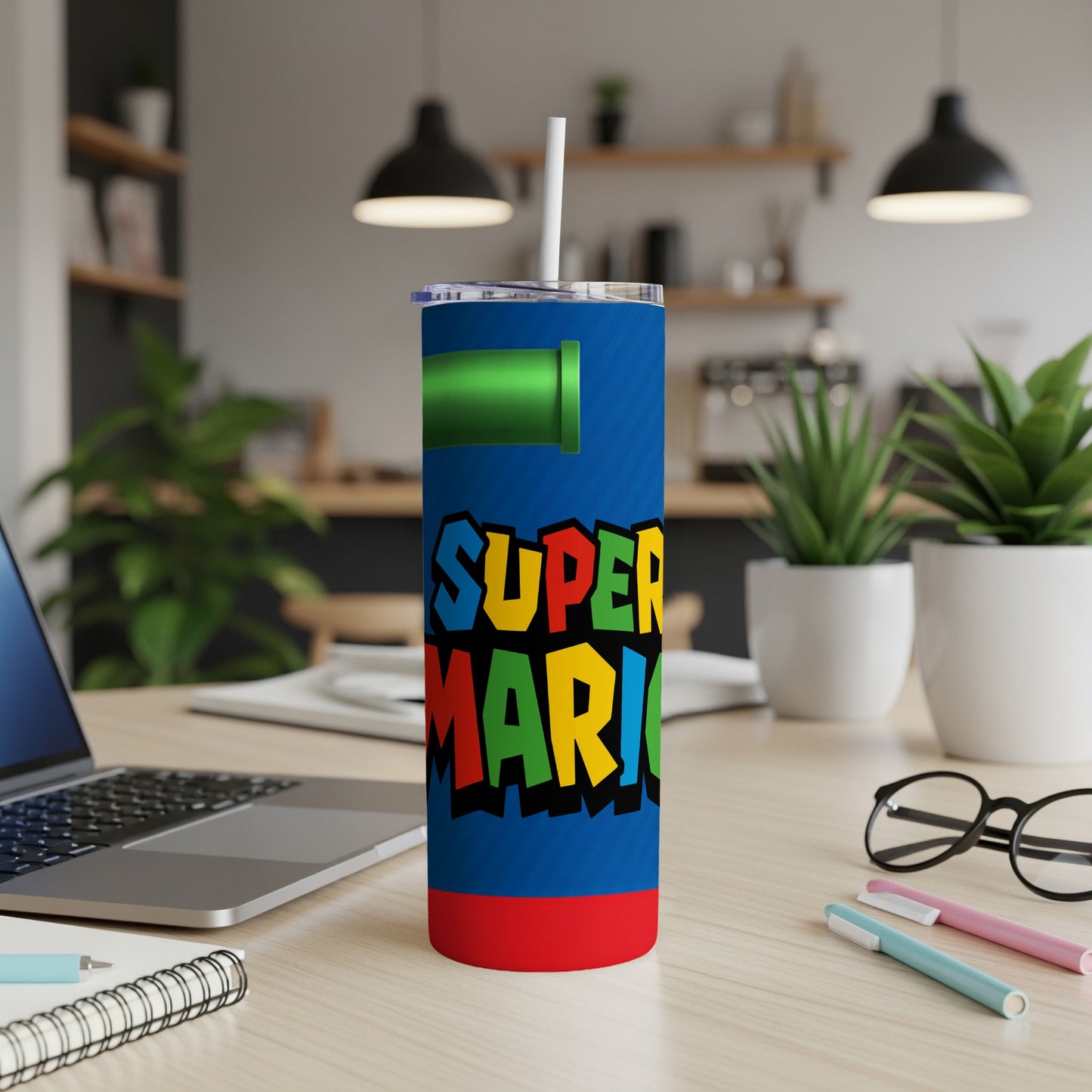 Super Mario tumbler with blue background and red base, on a desk.
