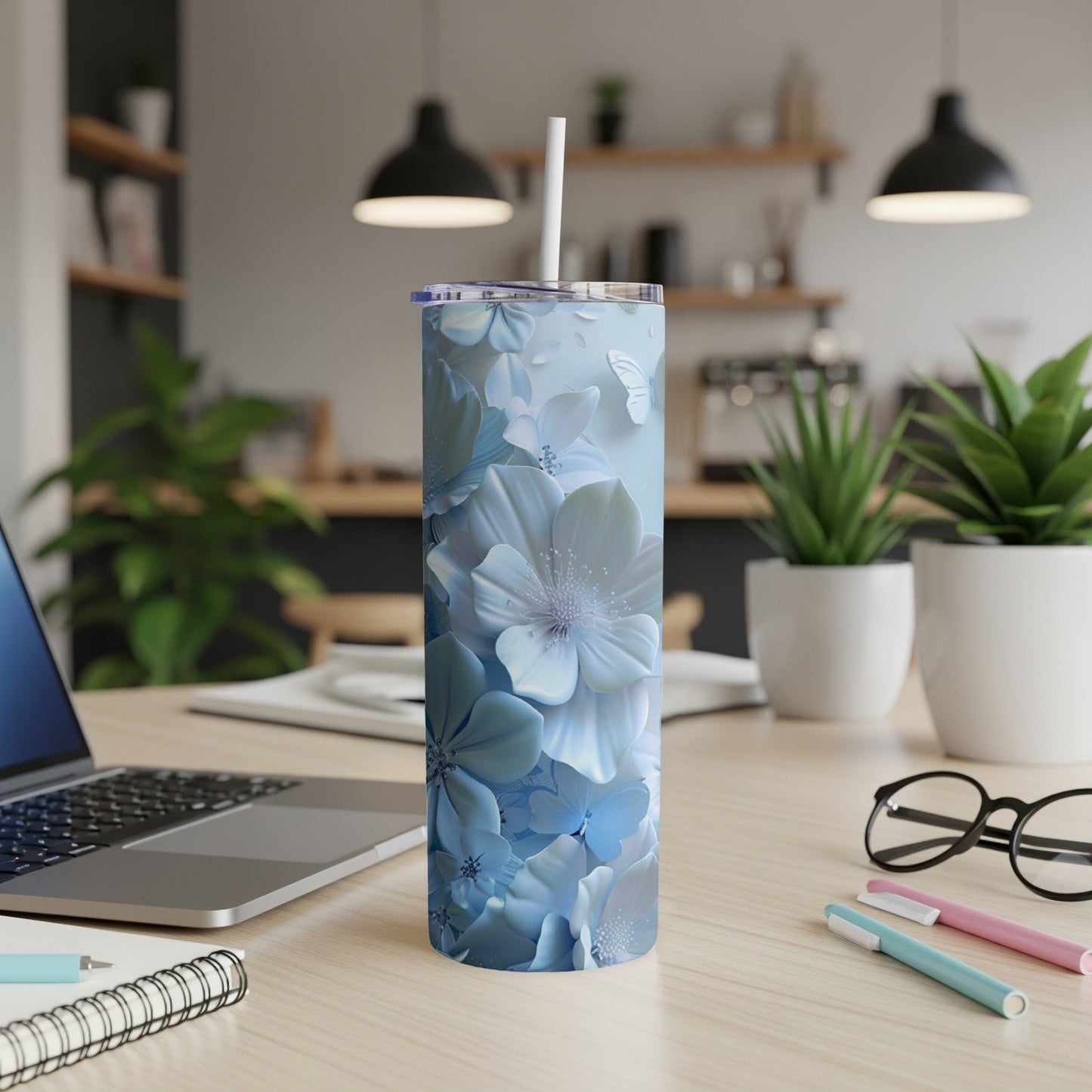 Blue floral pattern tumbler with white straw on a desk.