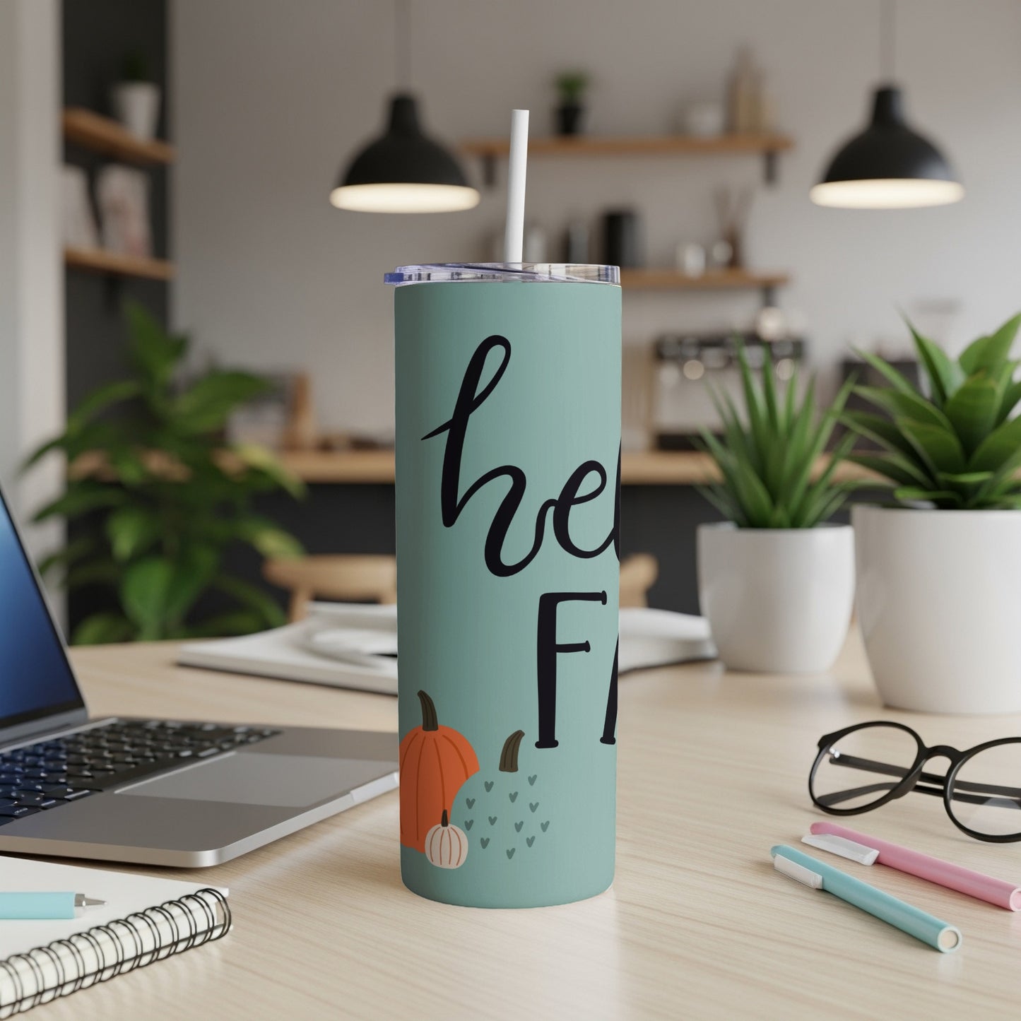 Mint green tumbler with "hello fall" text and pumpkins, on a desk.