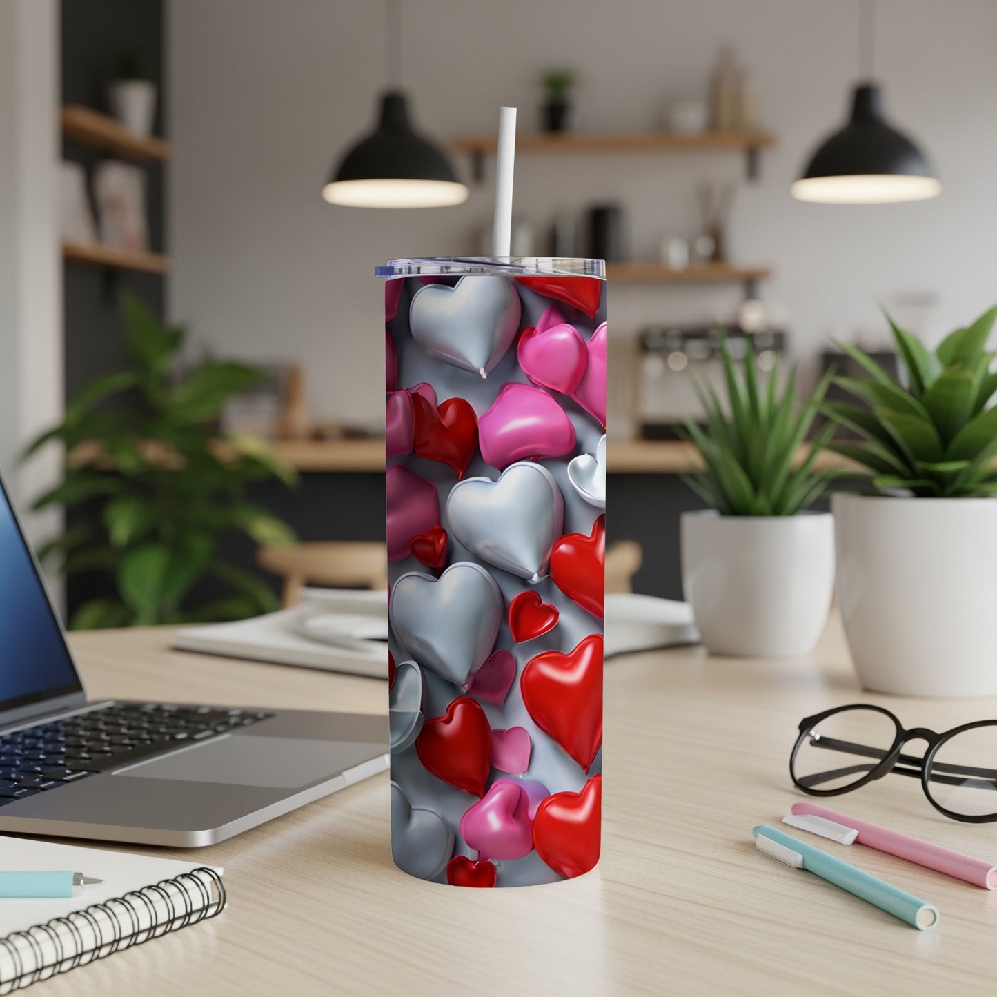 Pink, red, and silver hearts pattern on a tall tumbler with a straw.