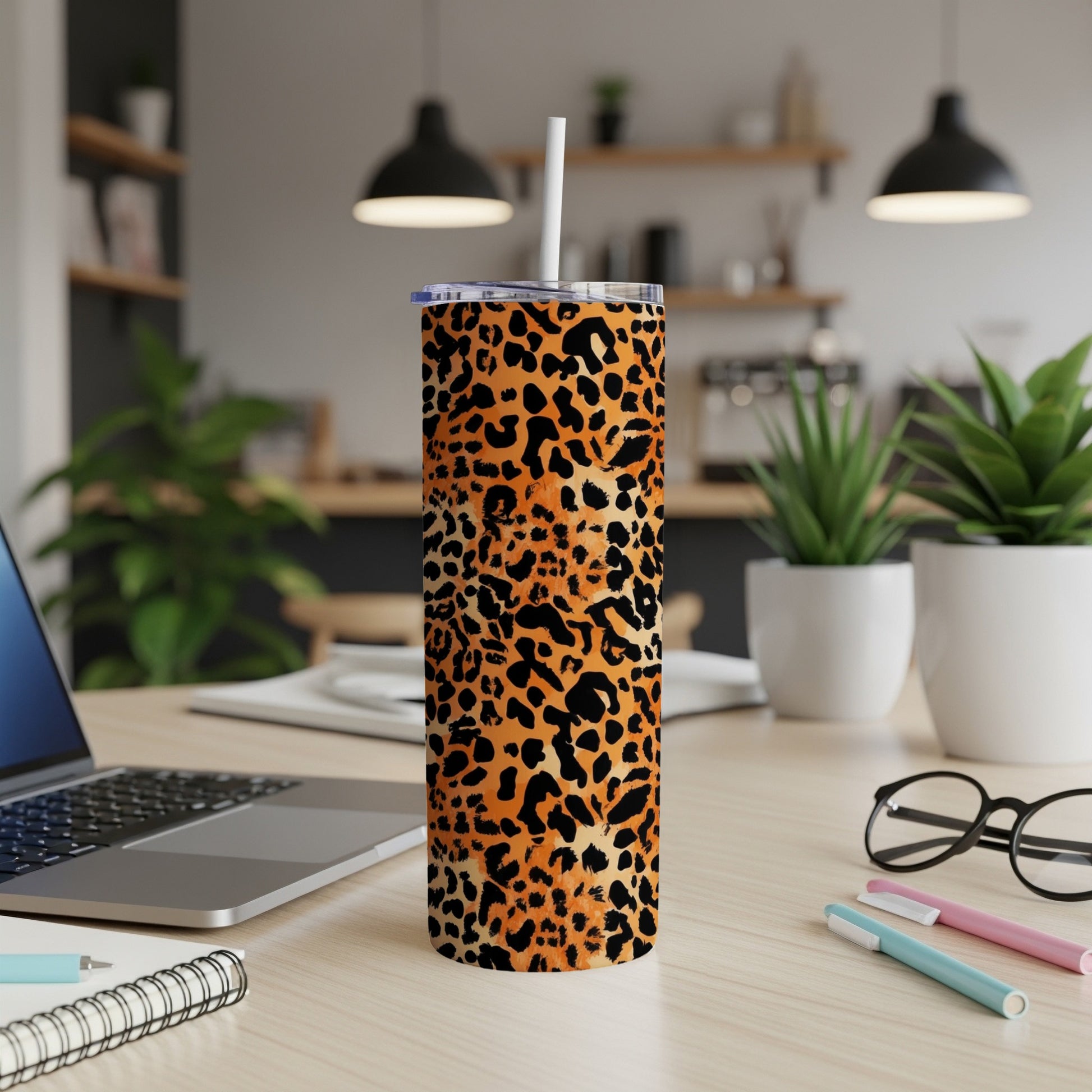 Leopard print tumbler with a straw on a desk, next to a laptop.