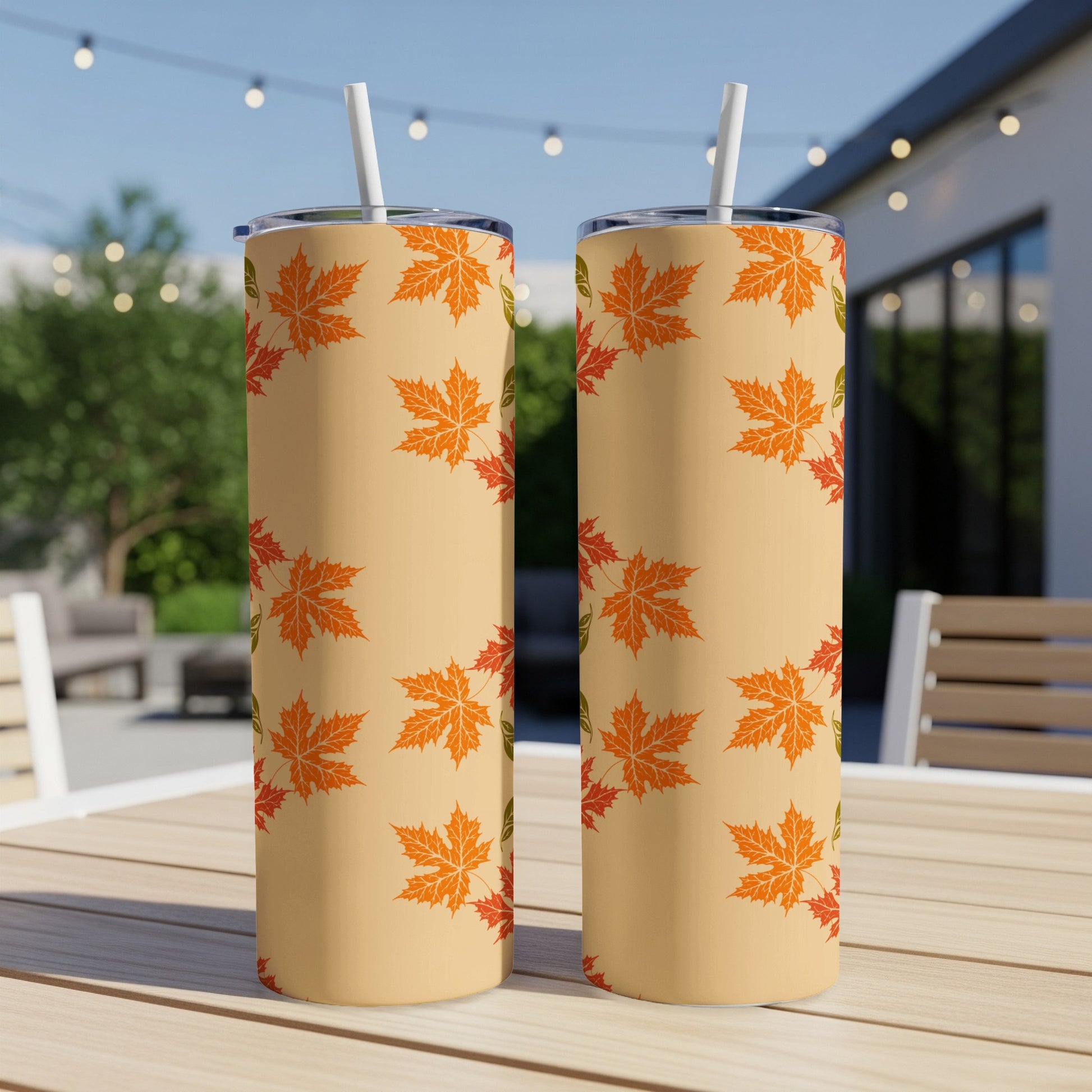 Two tan tumblers with orange and green maple leaf pattern.