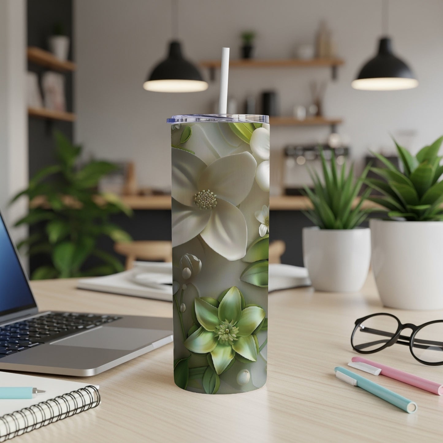 White and green floral pattern on a skinny tumbler with a straw.