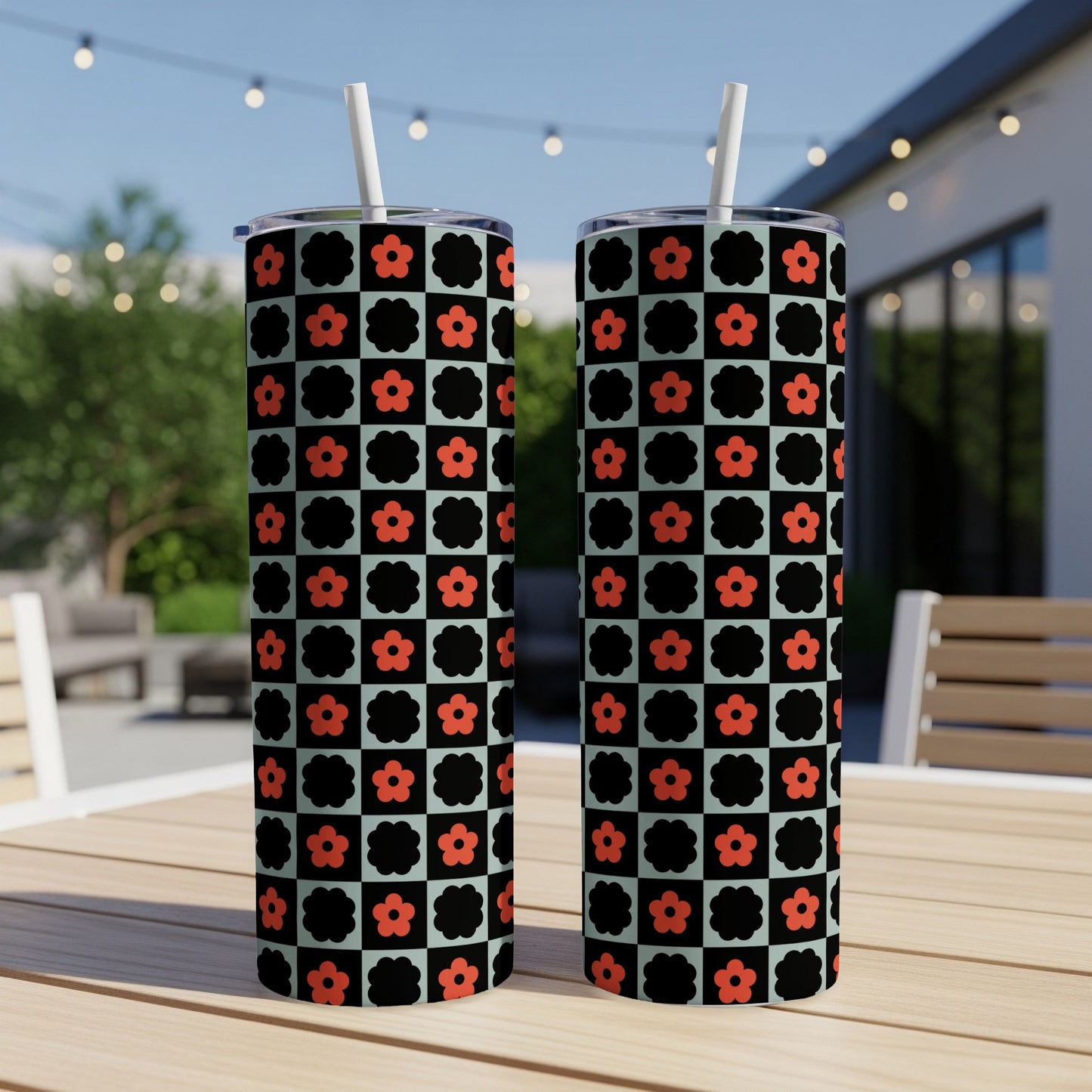 Two tall tumblers with a black and white checkered pattern and red flowers.