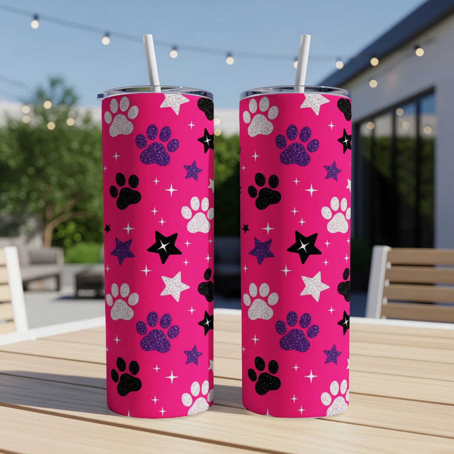 Two pink tumblers with glitter paw prints and stars on a wooden table.