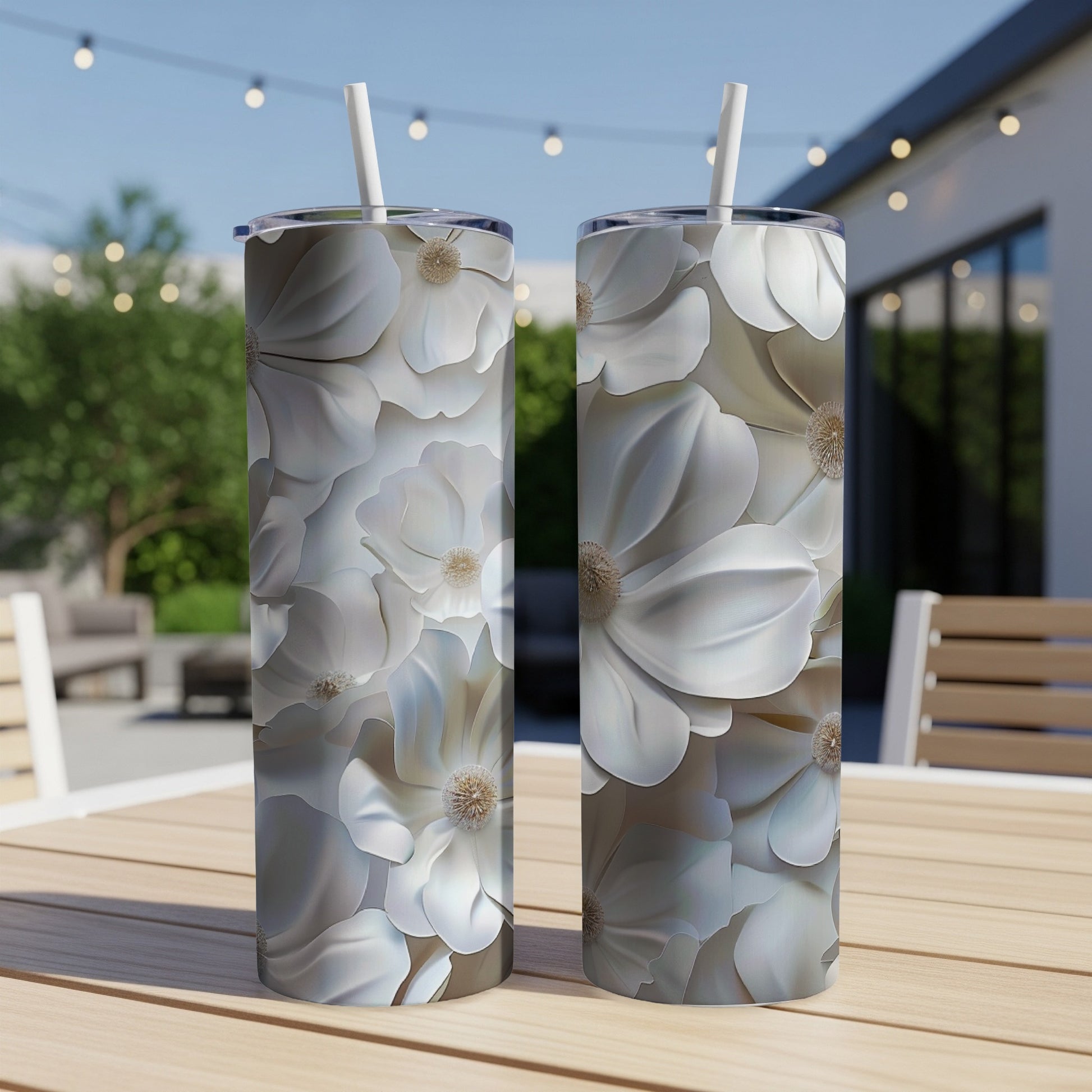 Two white floral pattern tumblers with straws sit on a table.