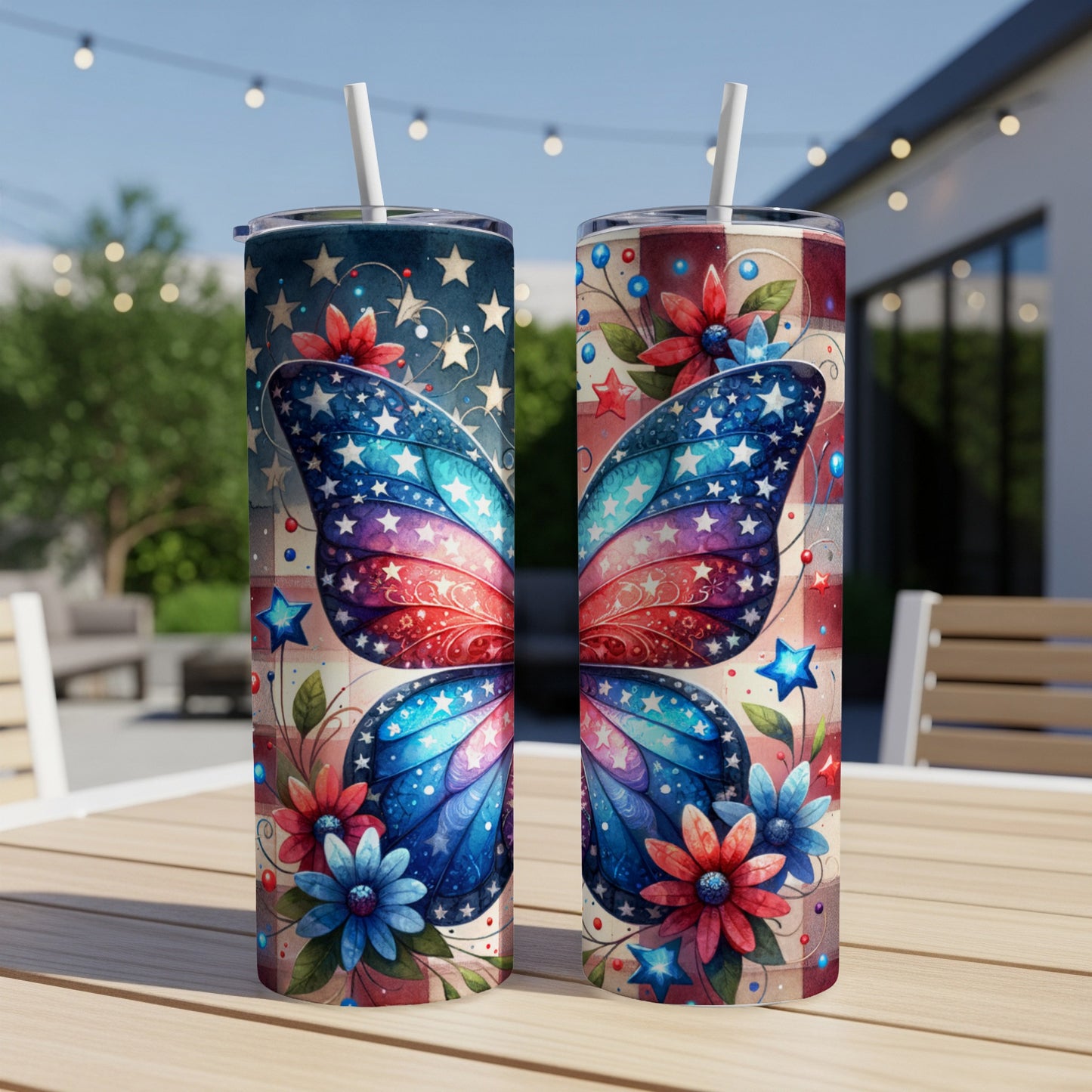 Two patriotic butterfly-themed tumblers with straws on a patio table.