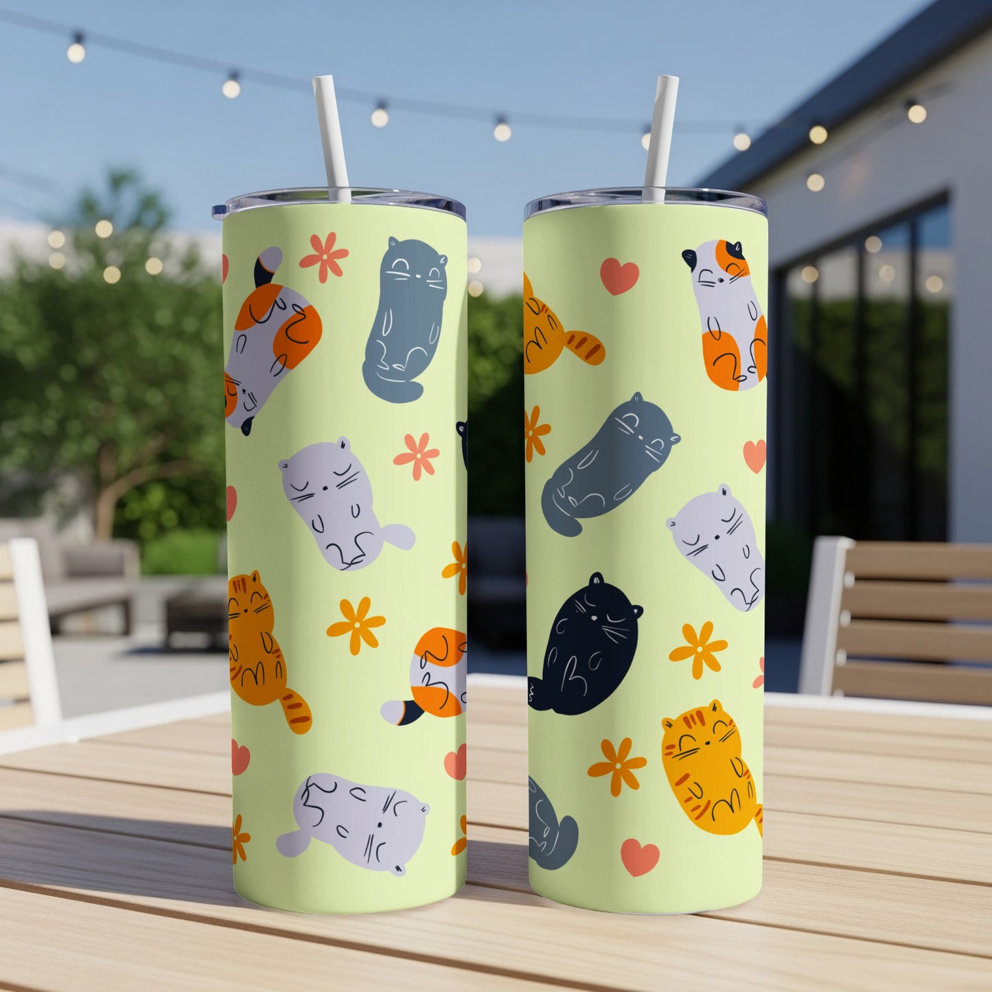 Two tall tumblers with cartoon cats and flowers on a light orange background.