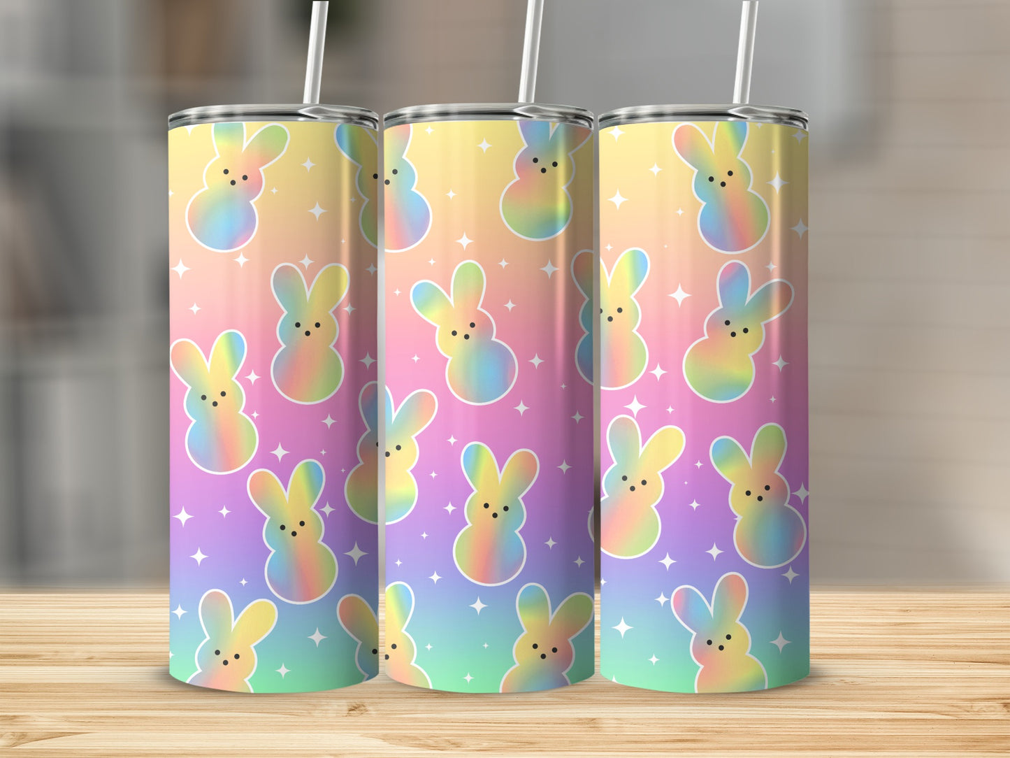 Three tumblers with pastel Easter bunny design on a wooden surface.