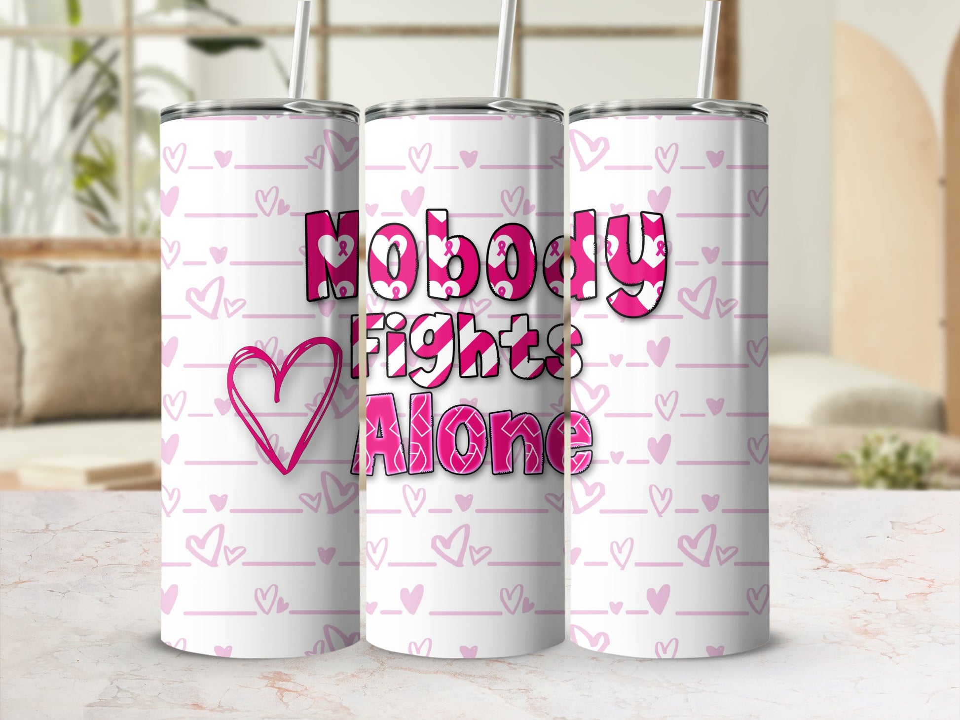 Pink tumbler with hearts and "Nobody Fights Alone" text.