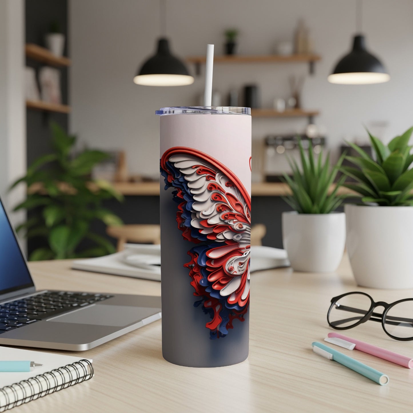 Butterfly wing pattern tumbler with straw on a desk.