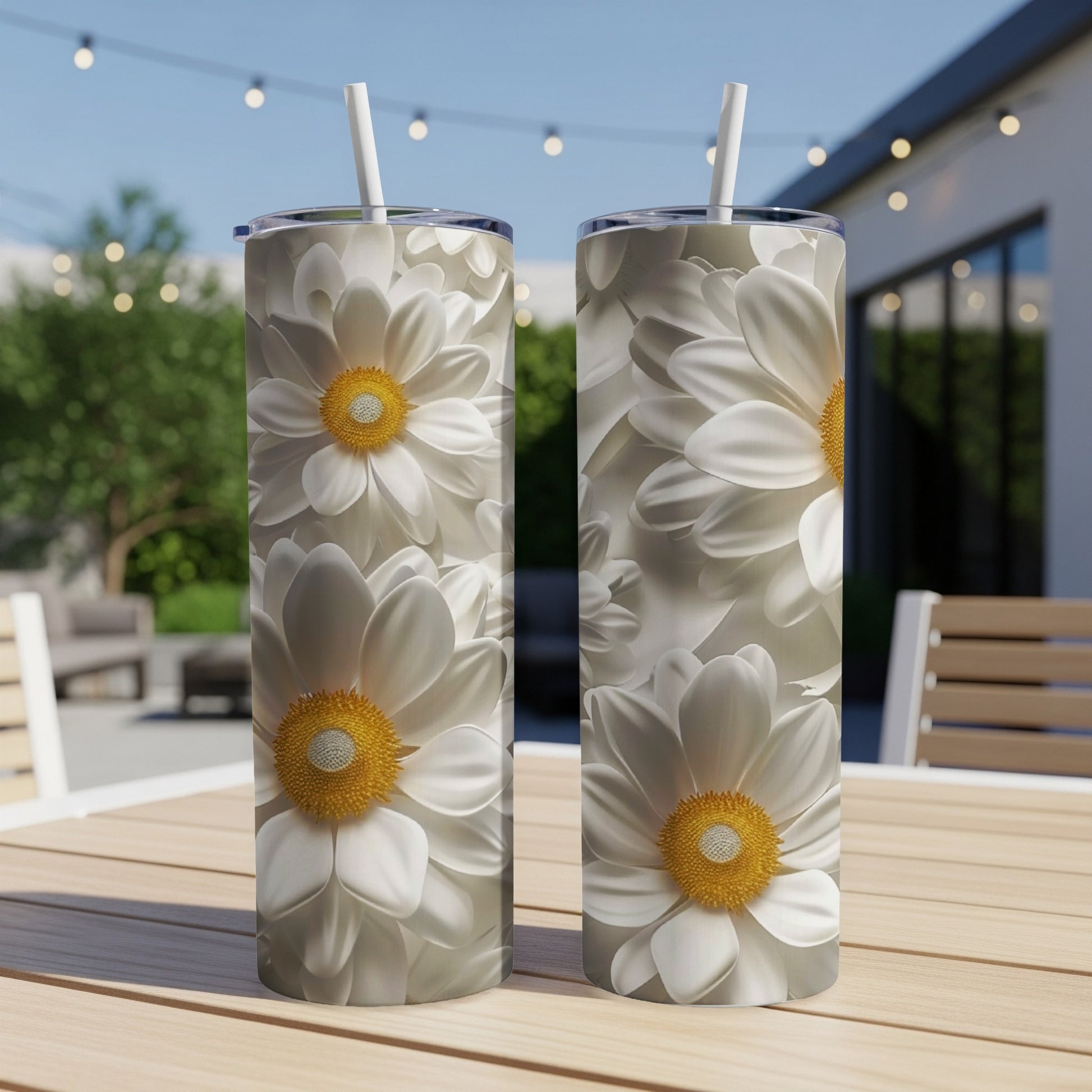 Two tall tumblers with a repeating pattern of white daisies on a wooden table.