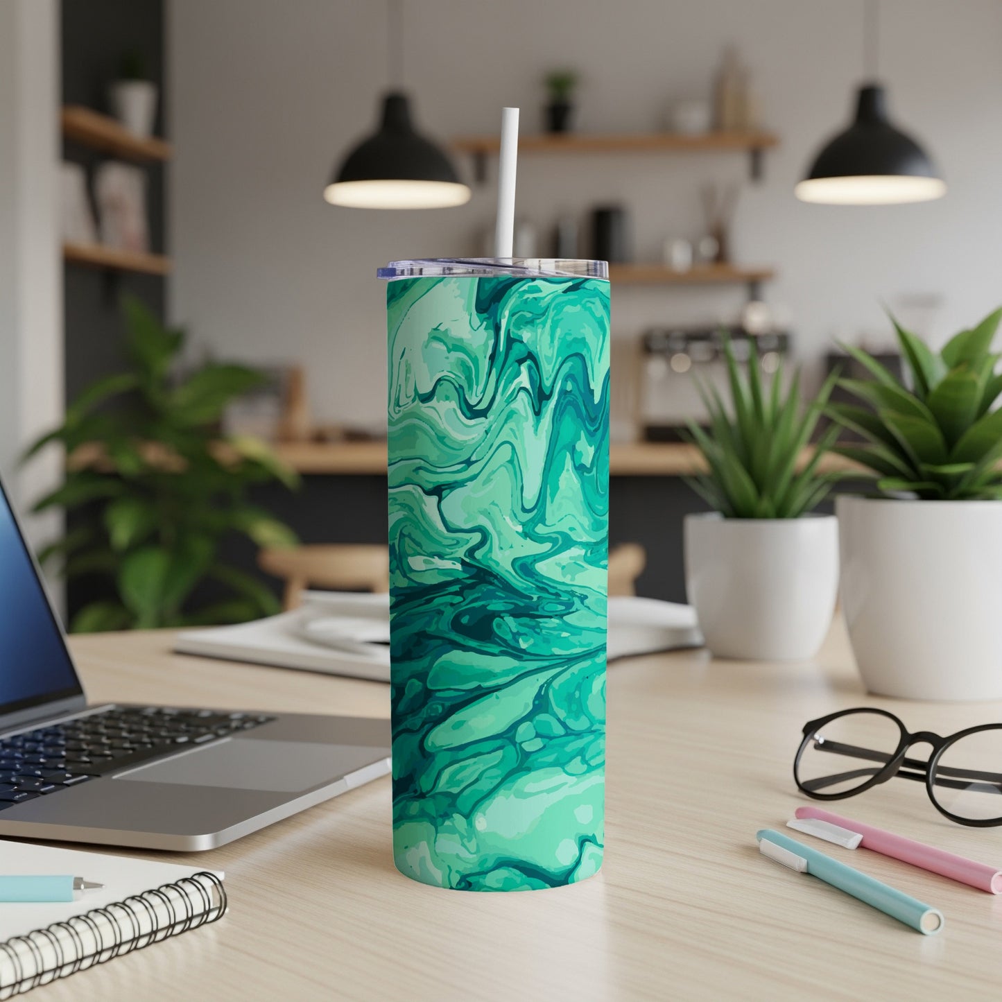 Teal and emerald green marble pattern tumbler with straw on a desk.