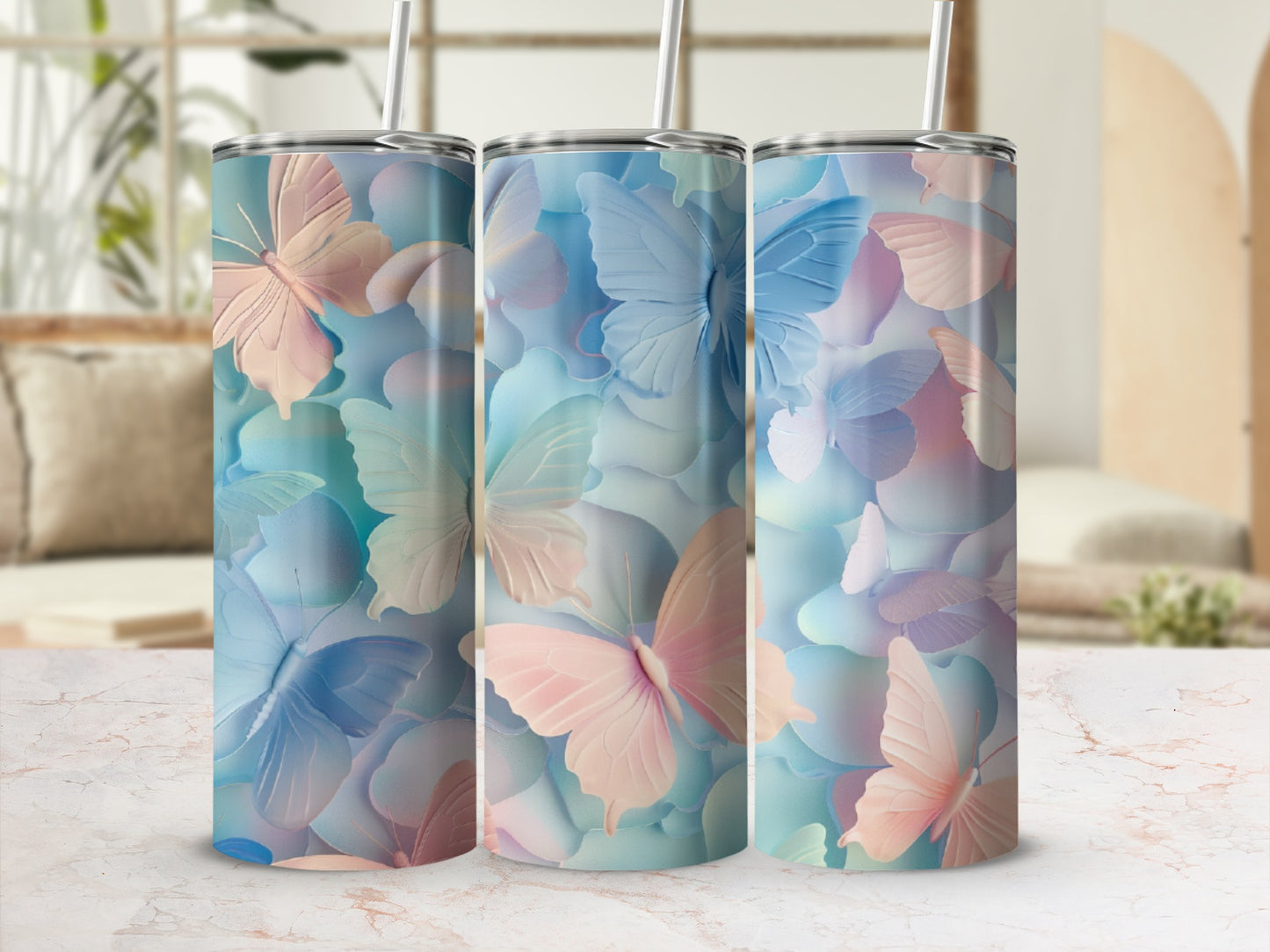 Three tall tumblers with pastel butterfly designs on a marble surface.