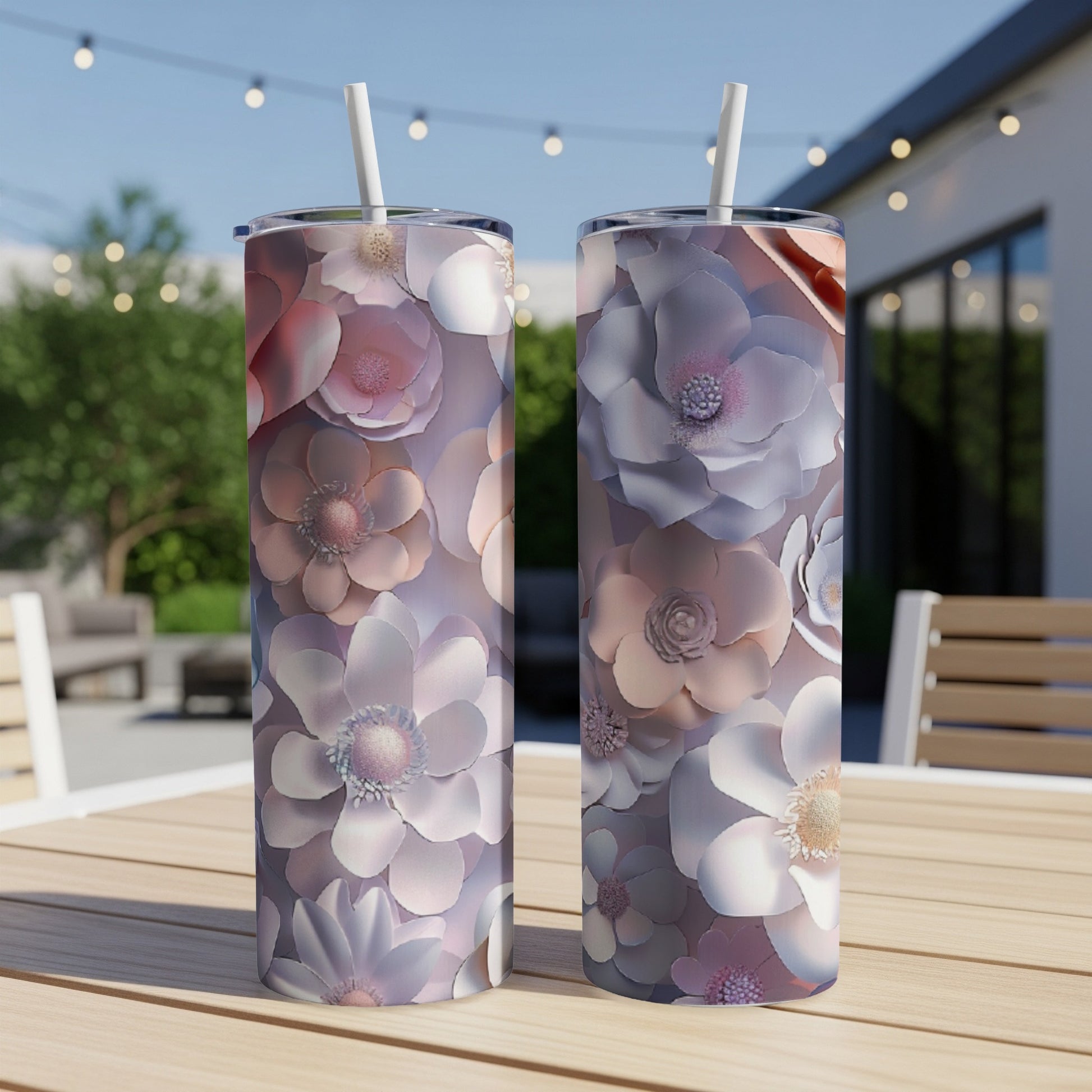 Two tumblers with a floral pattern sit on a table outdoors.
