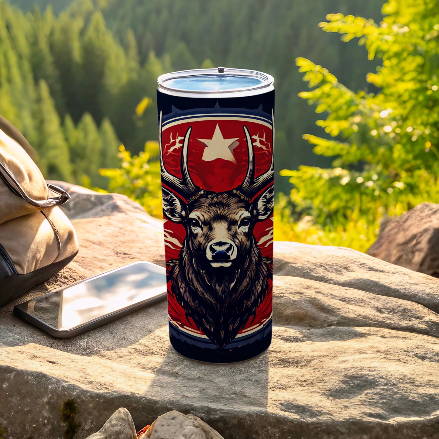 Tumbler with deer head design and star, resting on rocks.