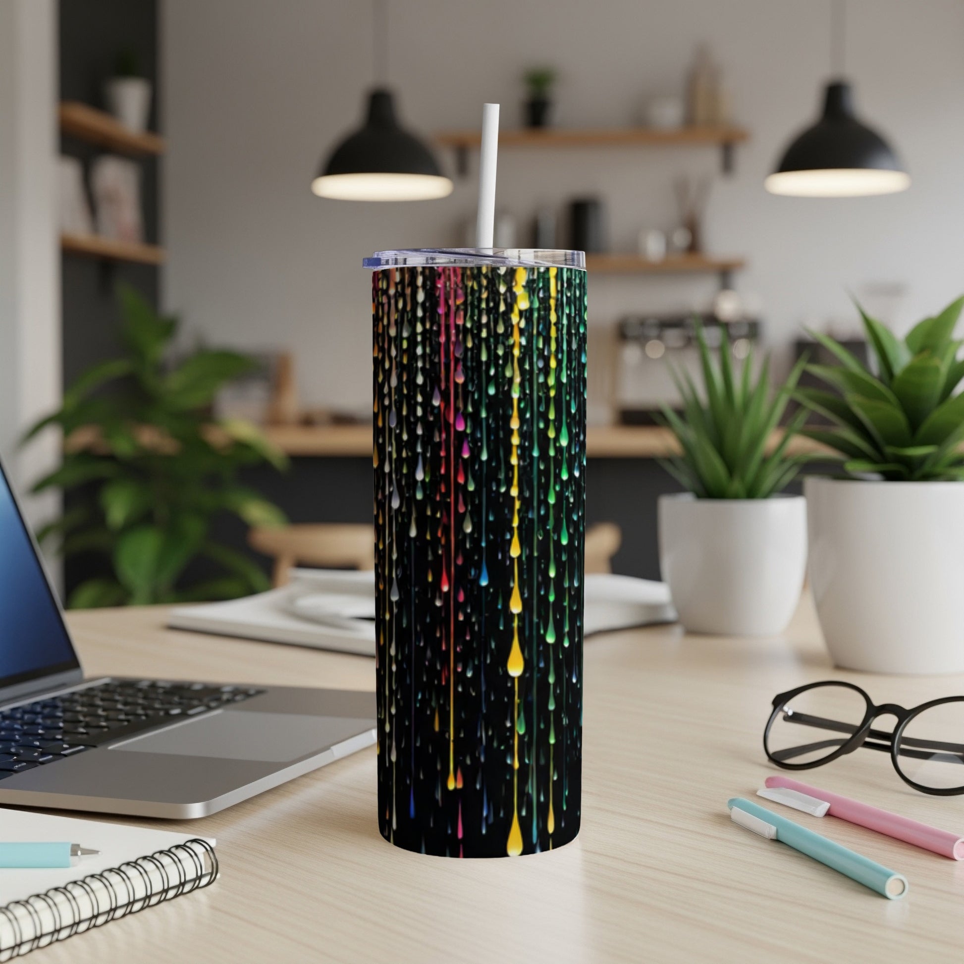 Black tumbler with colorful dripping paint design and straw.