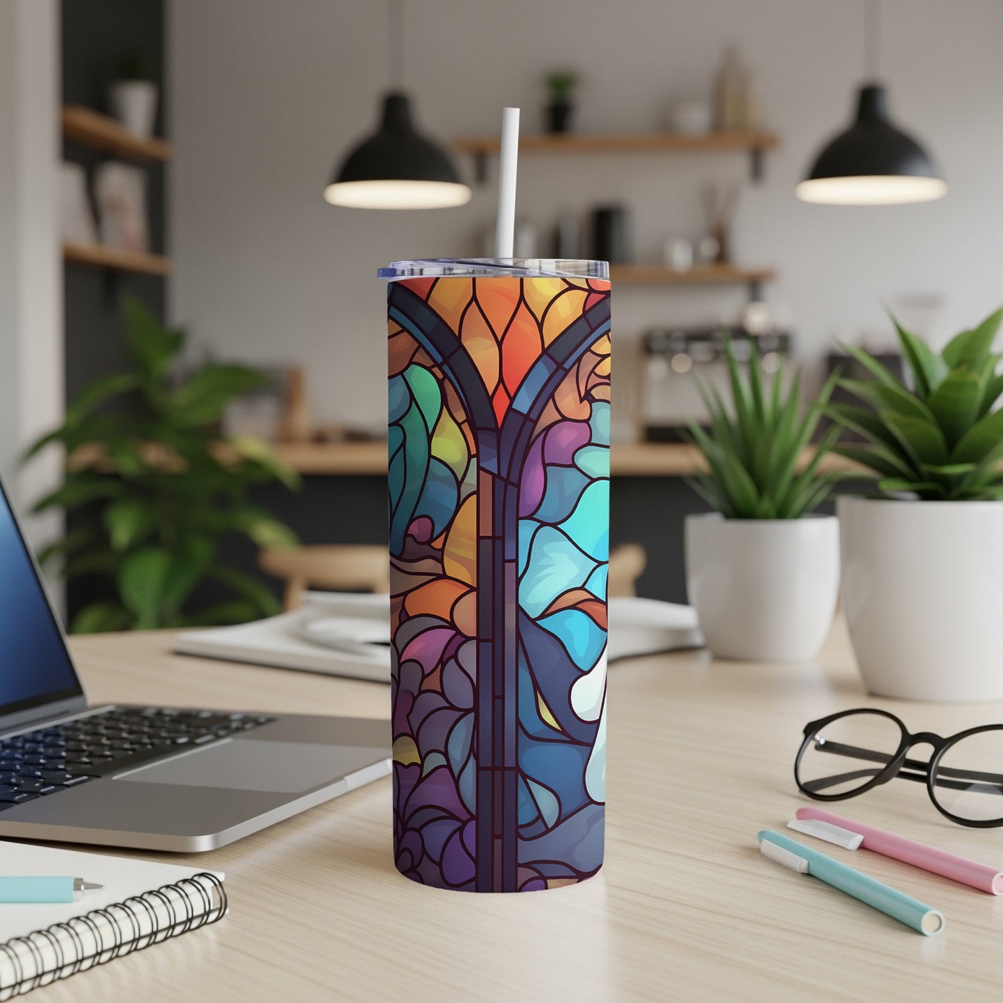 Tall tumbler with stained glass design and straw on a desk.