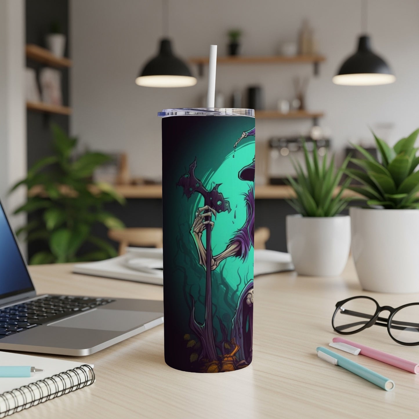 Tall tumbler with a spooky skeleton witch design and straw on a desk.