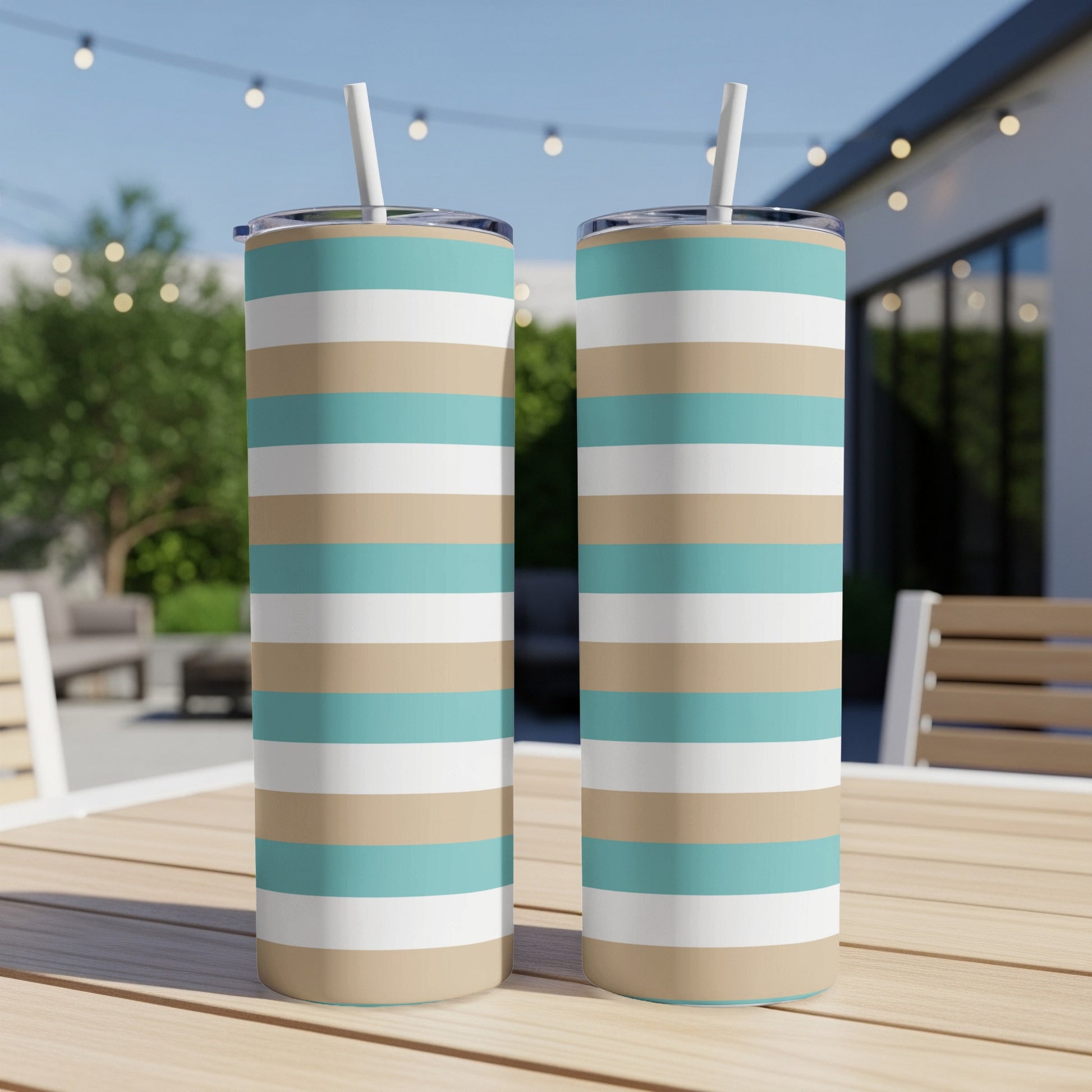 Two tall tumblers with blue, tan, and white horizontal stripes sit on a table.