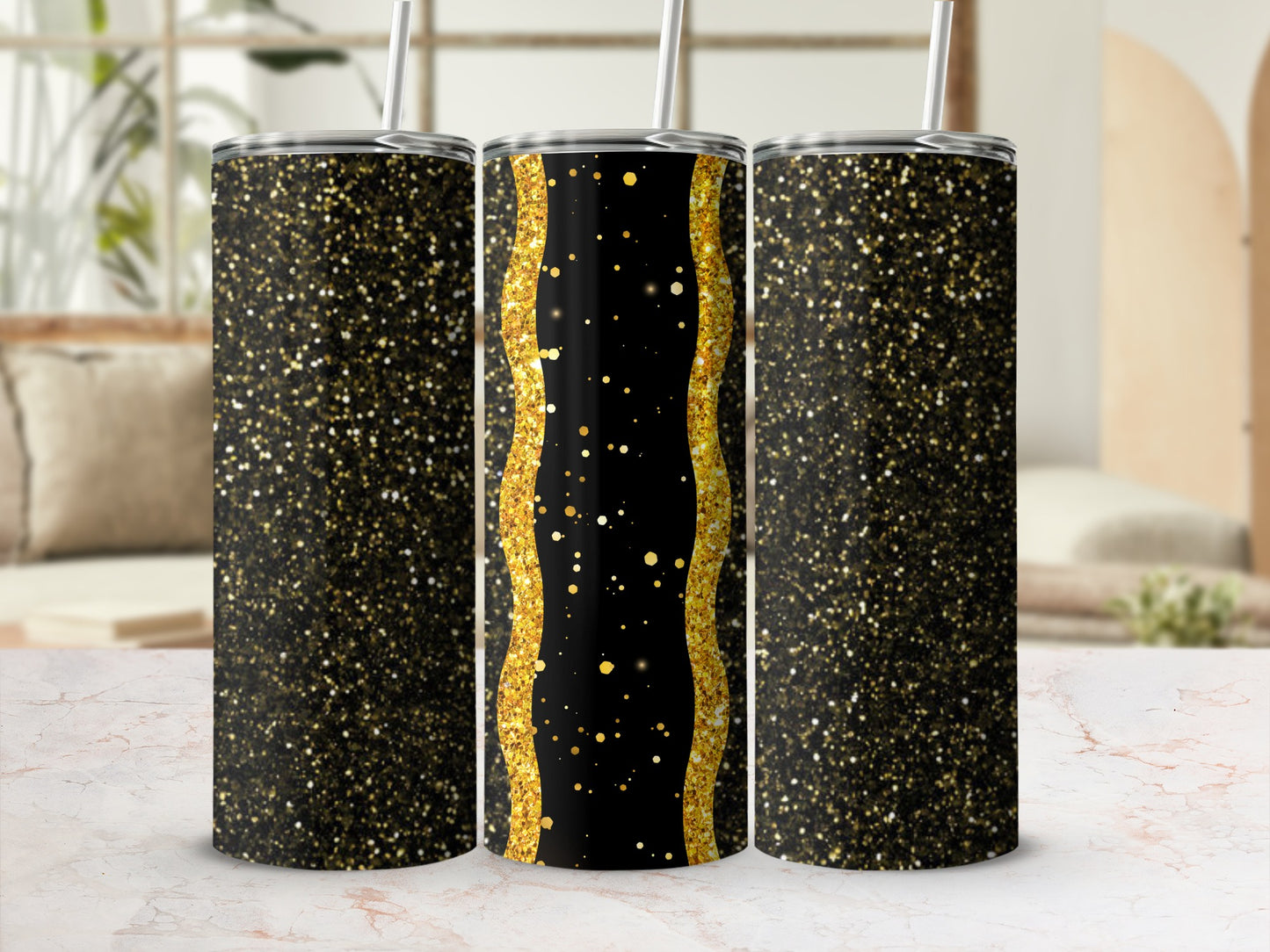 Three glittery black and gold tumblers with straws on a marble surface.