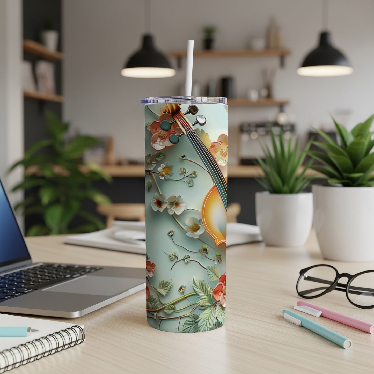 Tumbler with violin and floral design on a desk.