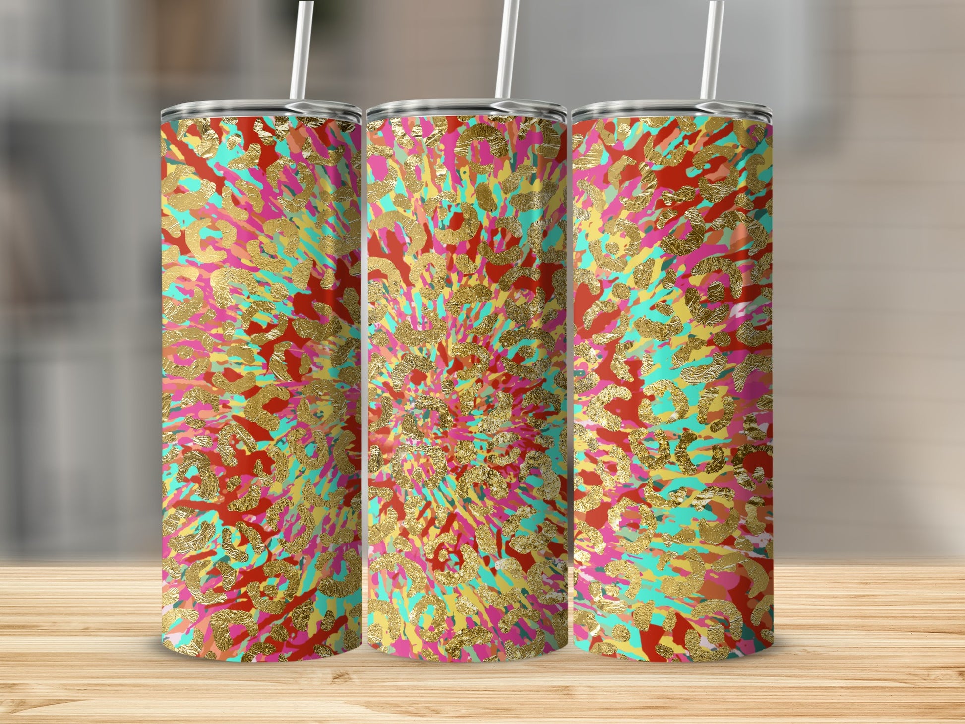 Three tumblers with a vibrant abstract splatter pattern of gold, red, pink, and teal.