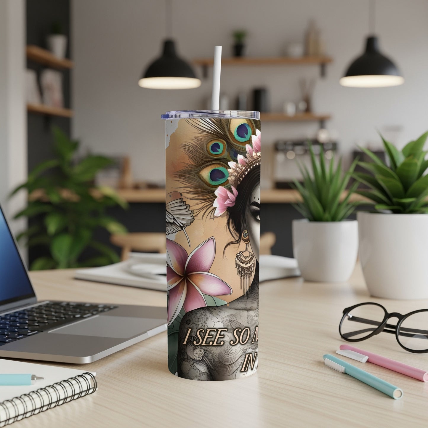 Tall tumbler with floral and peacock feather design, featuring a woman's face and text.