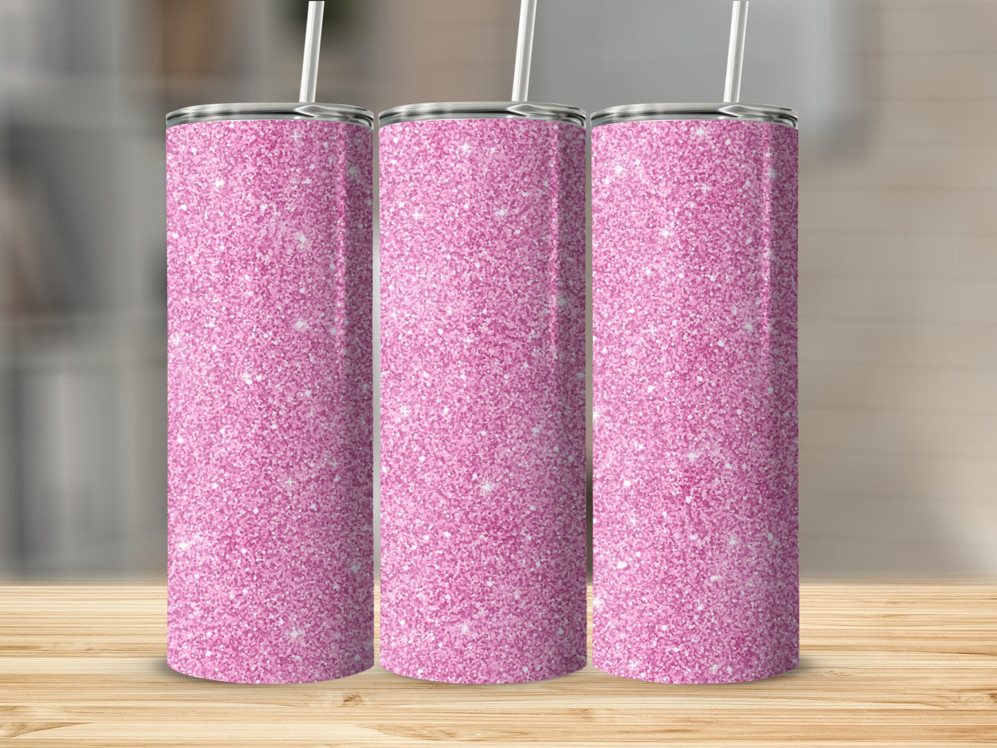 Three pink glitter tumblers with straws on a wooden surface.