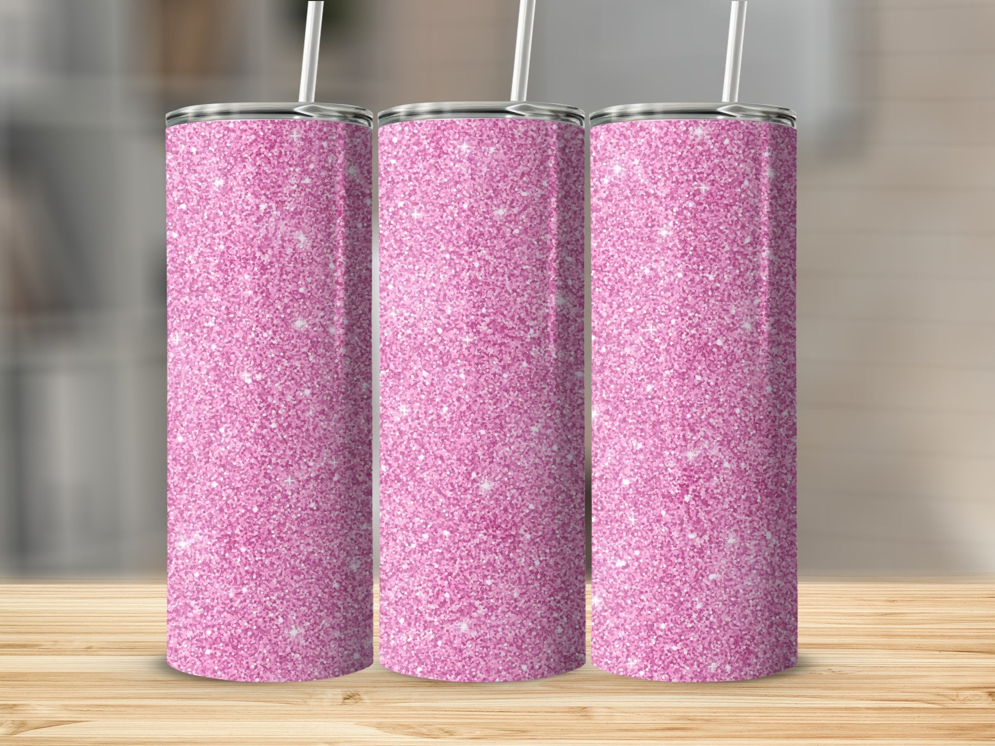 Three pink glitter tumblers with straws on a wooden surface.