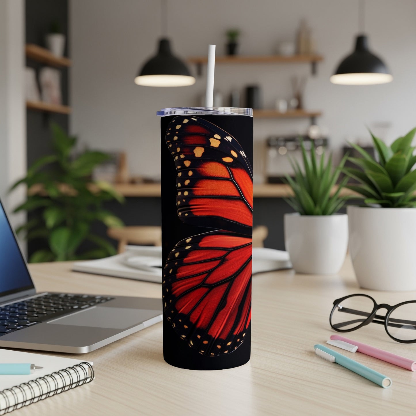 Monarch butterfly wing detail on a black skinny tumbler with a straw.