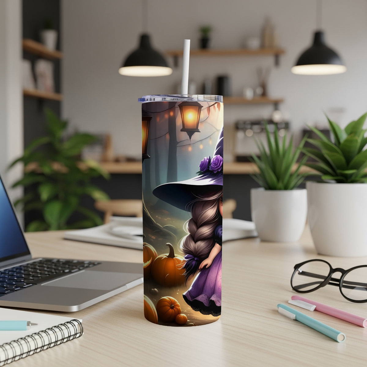 Halloween tumbler with witch, pumpkins, and lanterns on a desk.